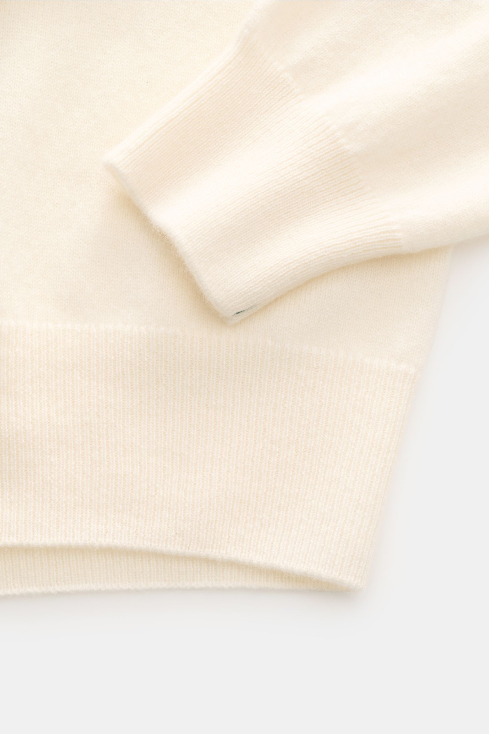 Close-up view of Fioroni Cashmere cardigan cream sleeve and hem, showcasing fine knit, soft pure cashmere, slim fit, smooth button placket, and flexible ribbed bands. Exquisite craftsmanship from Italy: This cardigan by FIORONI is precisely made from fine