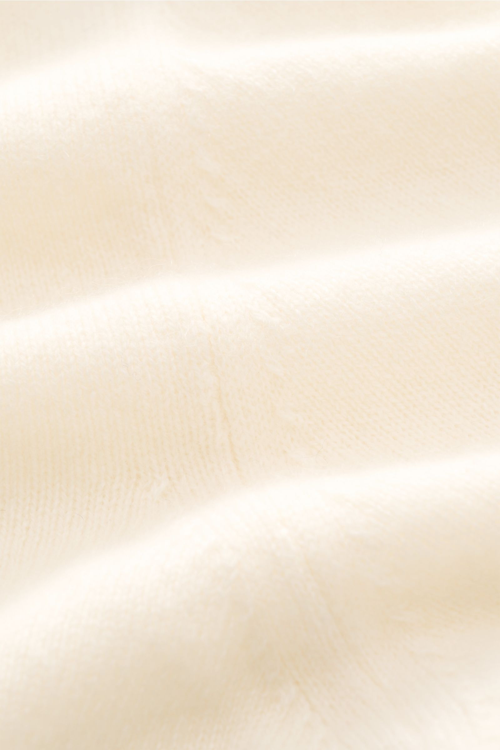 Close-up front-side view of Fioroni Cashmere cardigan cream showing fine knit, pure baby cashmere, smooth button placket, flexible ribbed bands, and slim fit. Exquisite craftsmanship from Italy: This cardigan by FIORONI is precisely made from fine materia