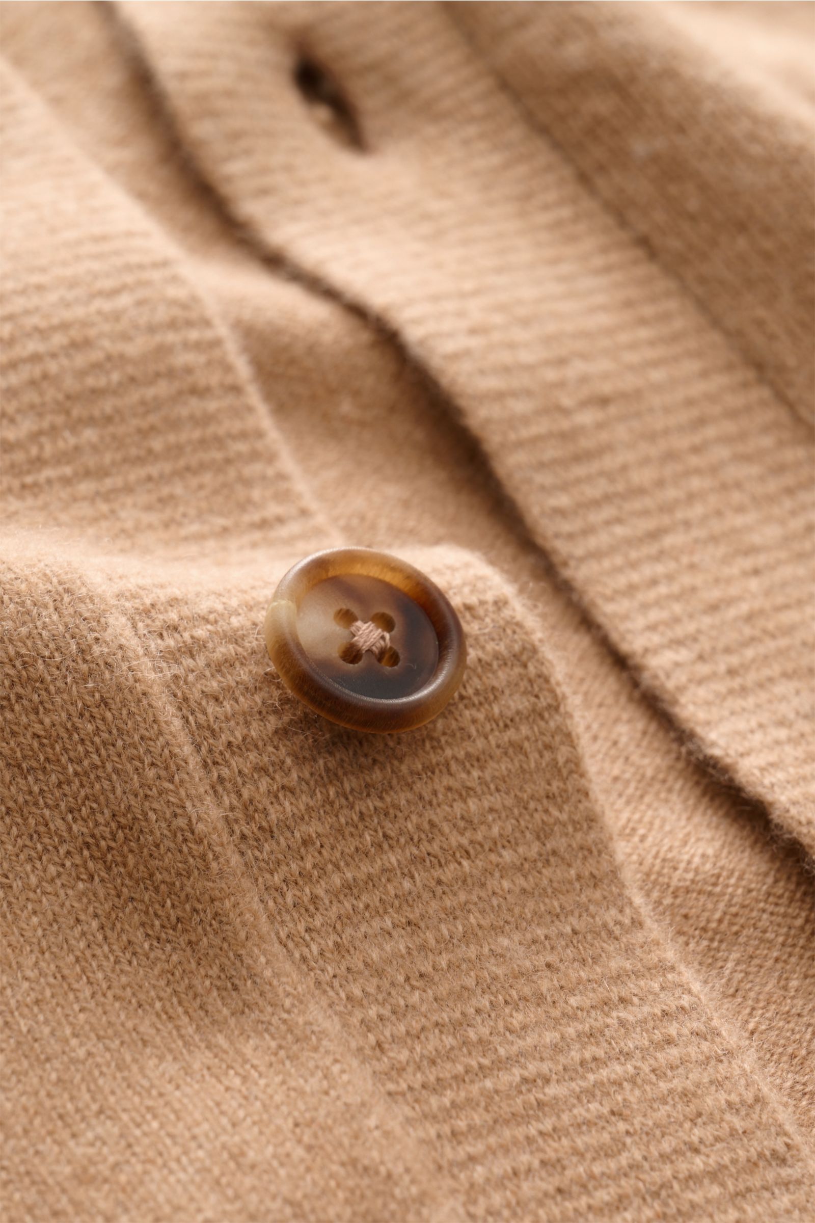 Close-up, angled view of the Fioroni Cashmere cardigan light brown mottled showing fine knit texture, smooth button placket with a brown button, and soft cashmere fabric. Exquisite craftsmanship from Italy: This cardigan by FIORONI is precisely made from 