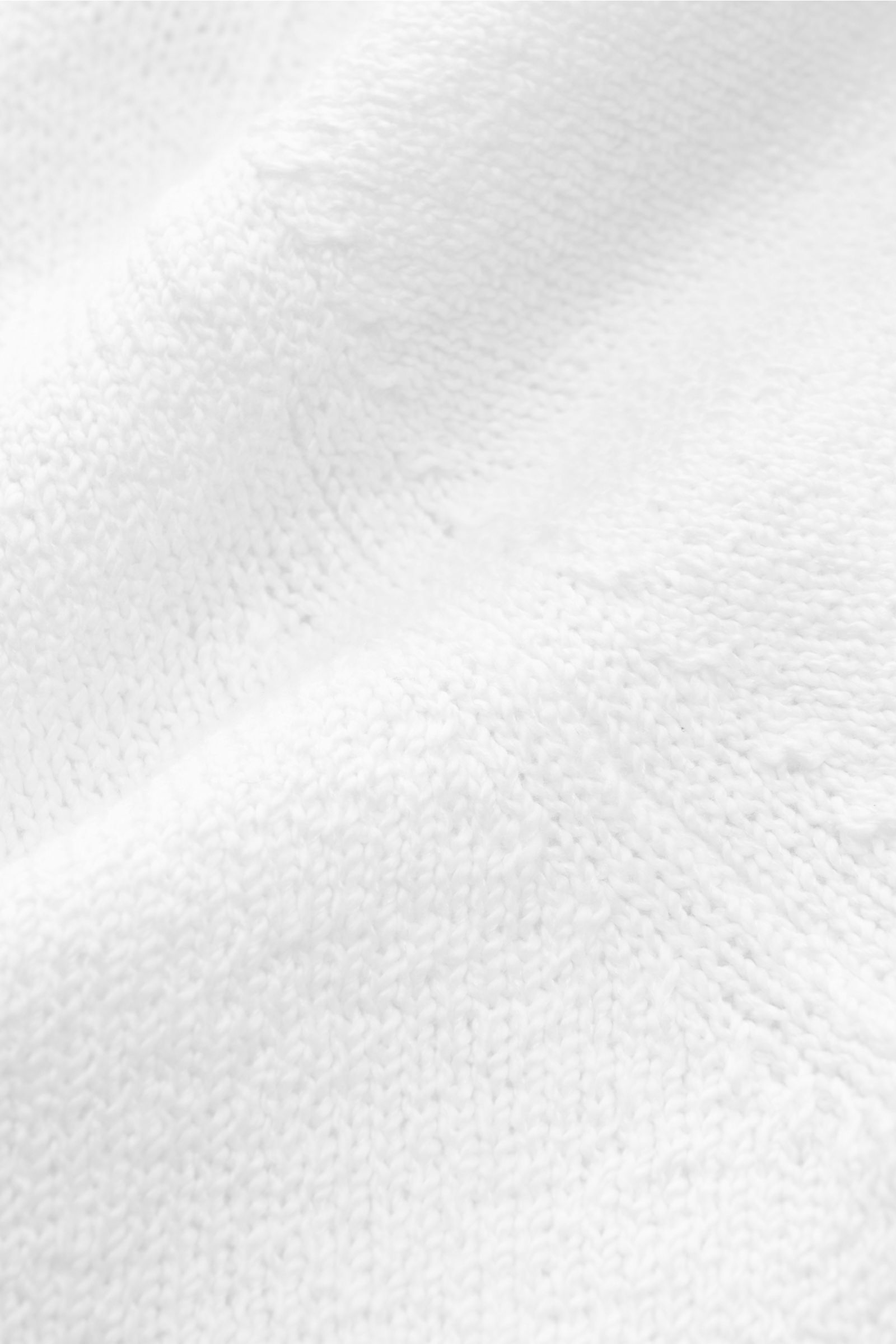 Fioroni Cardigan weiß aus reiner Baumwolle, Slim Fit mit Umlegekragen, acht Knöpfen, flexible Rippbündchen, Detailaufnahme des mittelfeinen Strickbilds.