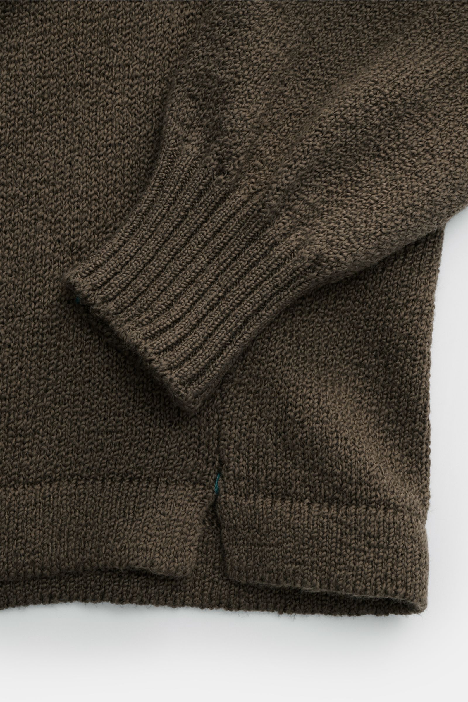 Nahaufnahme des olivfarbenen Fioroni Cardigan, seitliche Perspektive auf weichen Baumwollstoff mit flexiblem Rippbündchen, kurzem Saumschlitz und mittelfeinem Strickbild.