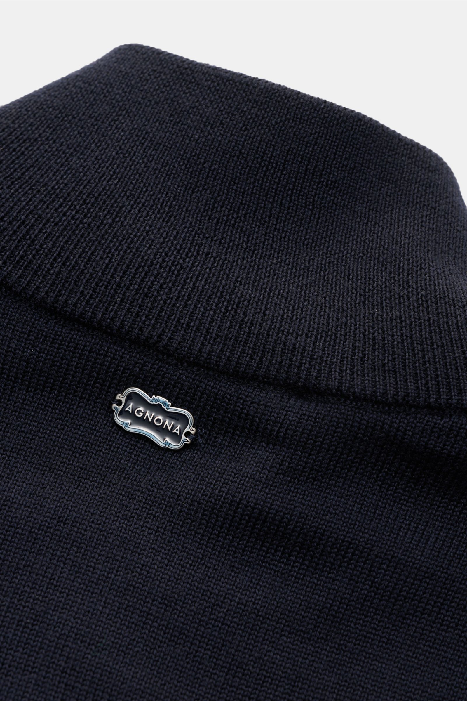 Nahaufnahme der Agnona Strickjacke navy aus reiner, weicher Wolle mit hoch schließendem Kragen, Metall-Logo und Rippbündchen.