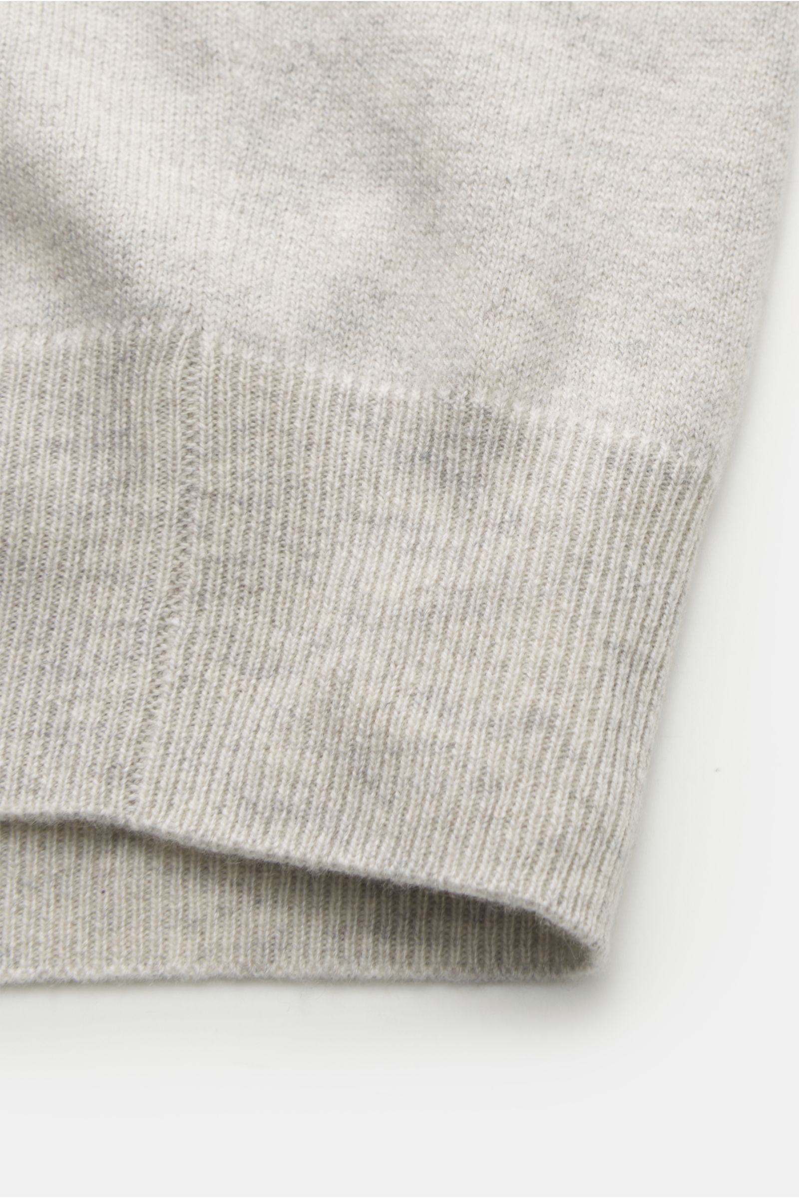 Close-up from a top-down perspective of the sleeve cuff showing the fine knit and ribbed hem of the Brunello Cucinelli Cashmere Strickjacke hellgrau meliert.

Luxus für die Freizeitgarderobe bietet BRUNELLO CUCINELLI mit dieser Strickjacke aus geschmei