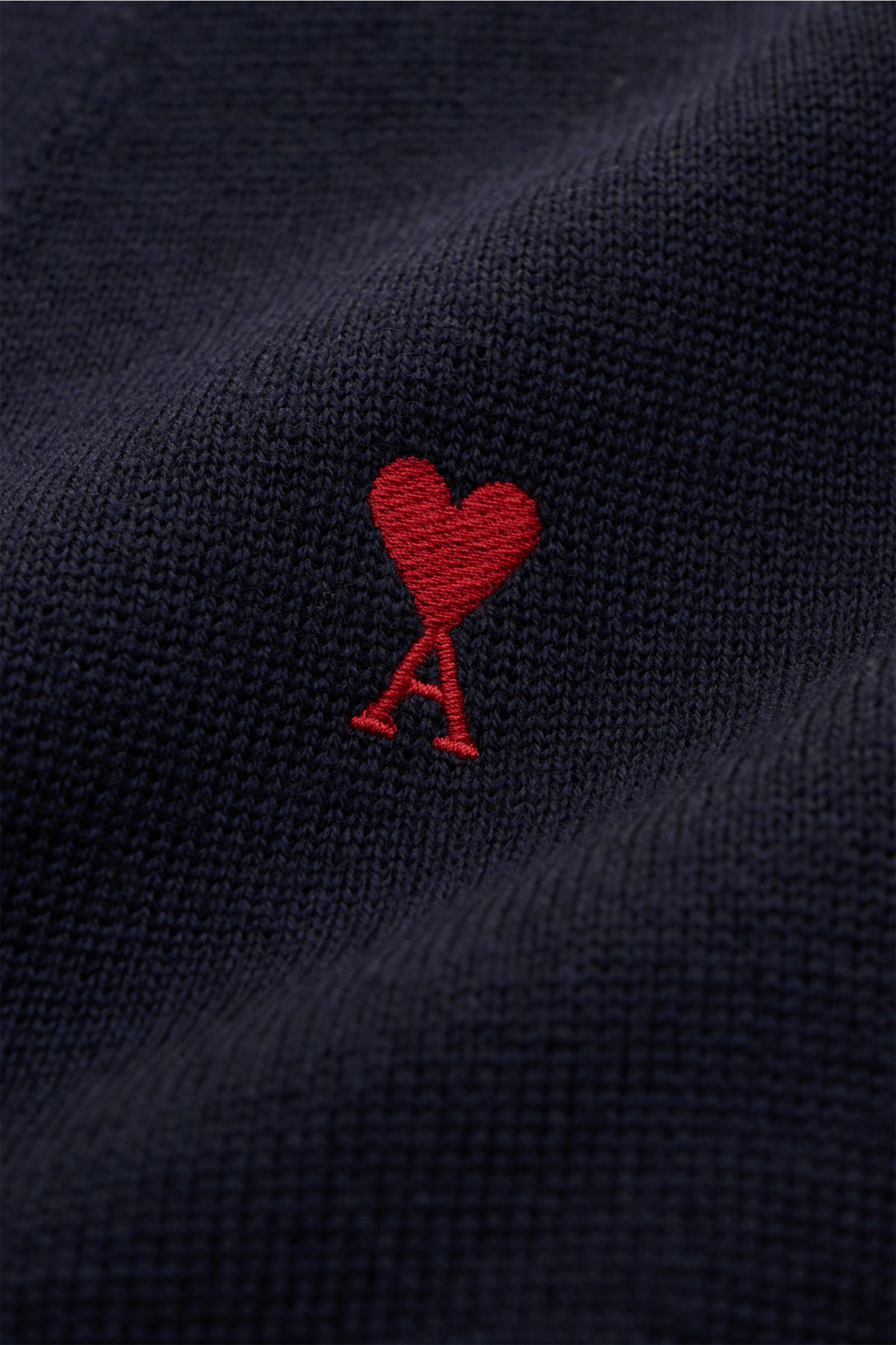 Nahaufnahme des roten 'Ami de Cœur'-Monogramms auf dem navyfarbenen Ami Paris Merino Cardigan navy aus weicher Merinowolle.