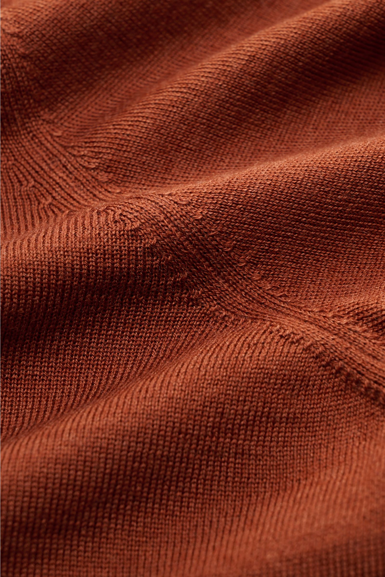 Nahaufnahme des BRAUN Hamburg Cardigans rostbraun, fotografiert aus schräger Perspektive, zeigt superfeines Strickbild, weiche Haptik dank Schurwolle, Cashmere und Seide, Slim Fit mit V-Ausschnitt, Fünf-Knopf-Leiste und Rippbündchen.