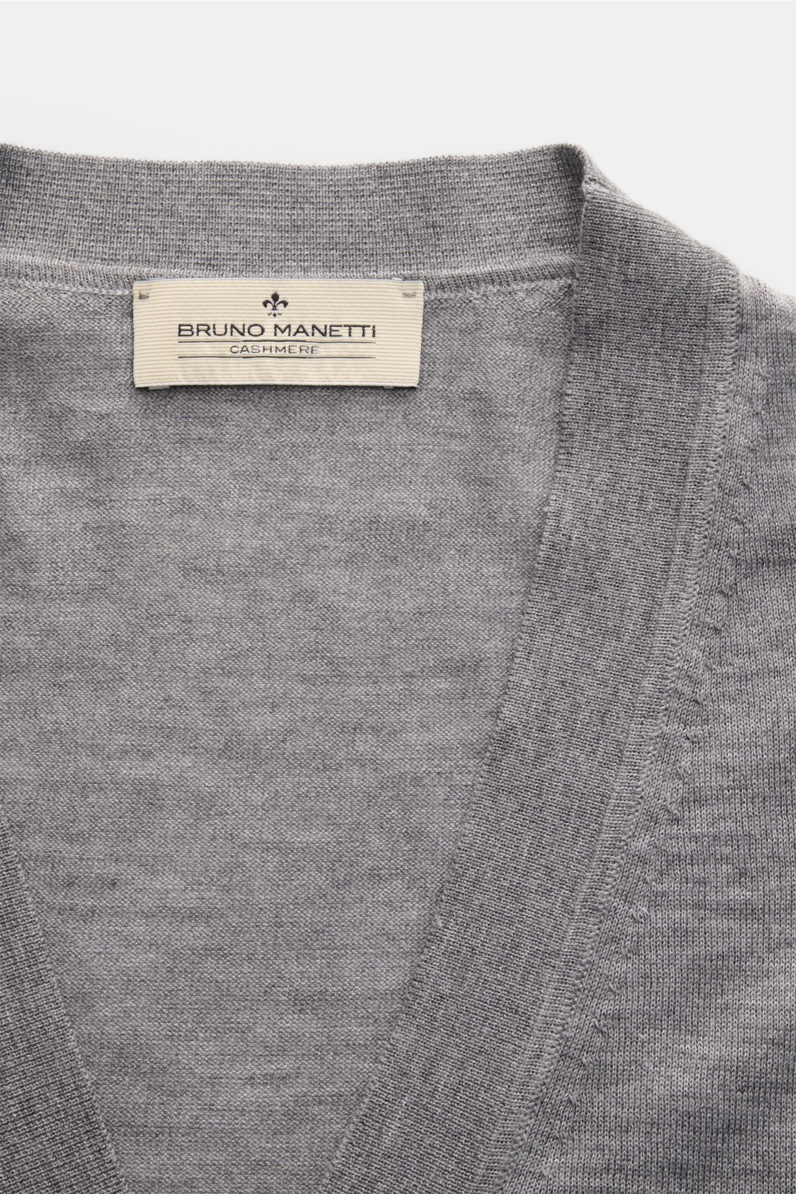 Close-up front view of the Bruno Manetti Cashmere-silk cardigan grey mottled showing fine knit V-neck and label. Luxury you can feel on your skin: This fine knit cardigan by BRUNO MANETTI has an exceptionally soft feel and timeless elegance. The luxurious