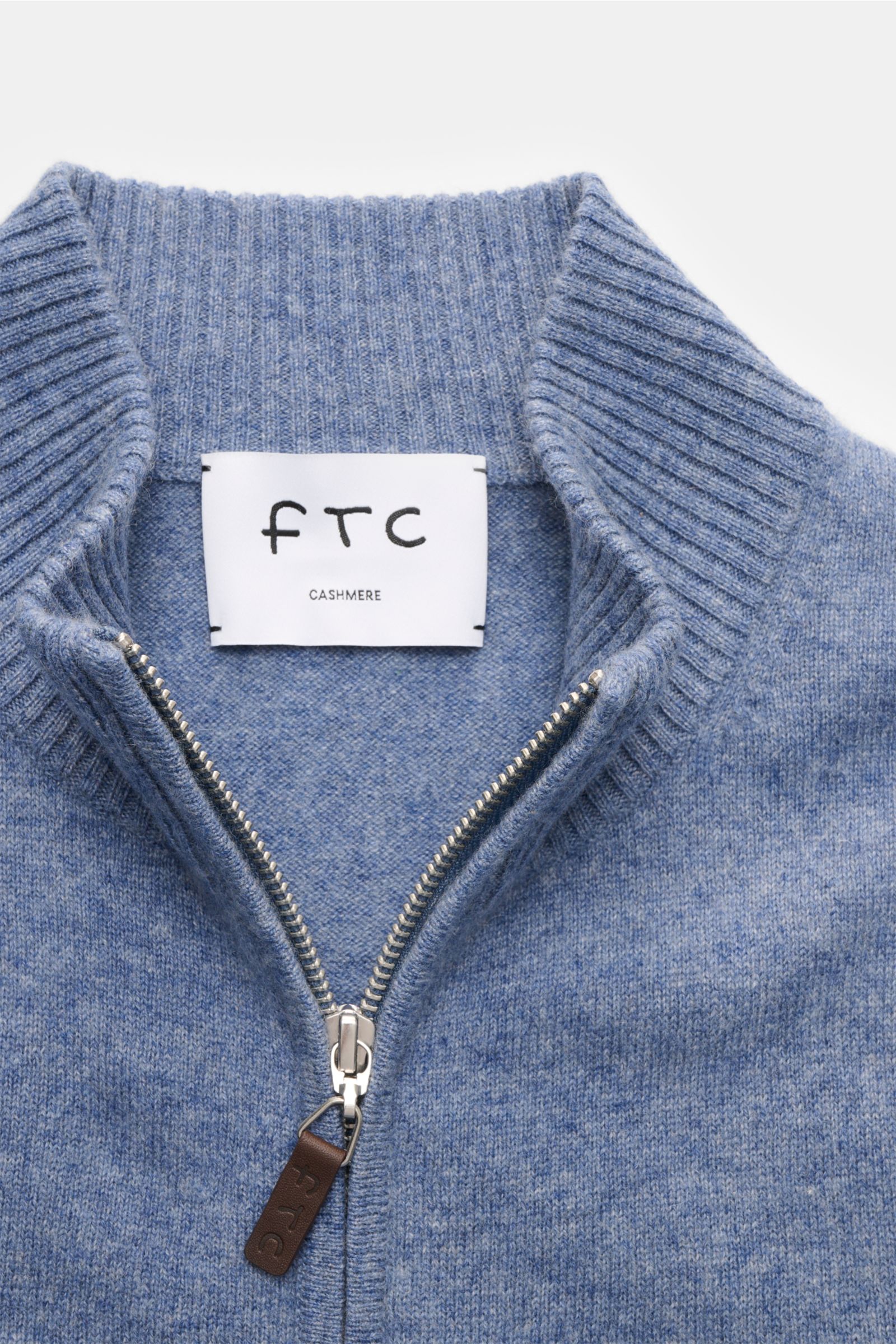 Nahaufnahme der FTC Cashmere Strickjacke rauchblau meliert mit geripptem Stehkragen, verdecktem Zwei-Wege-Reißverschluss und Leder-Logozipper.