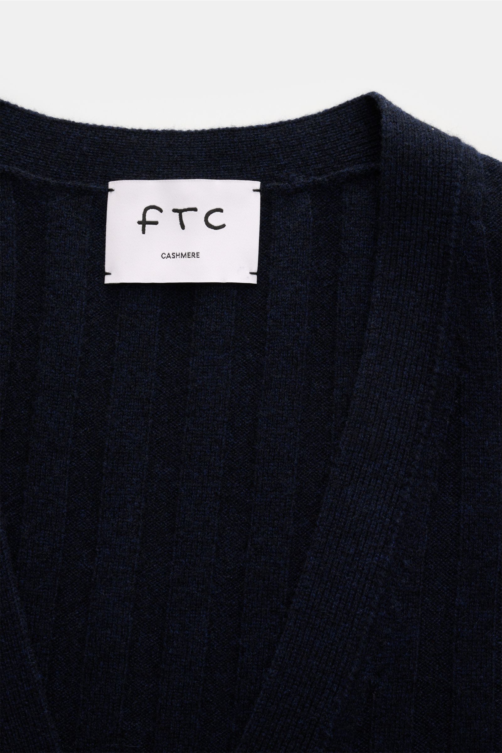 Close-up front view of the FTC Cashmere cardigan navy showing wide rib knit, V-neck, and label.

This luxurious cardigan by environmentally friendly knitwear label FTC is a soft essential made of pure fair trade cashmere in a college design and a moder