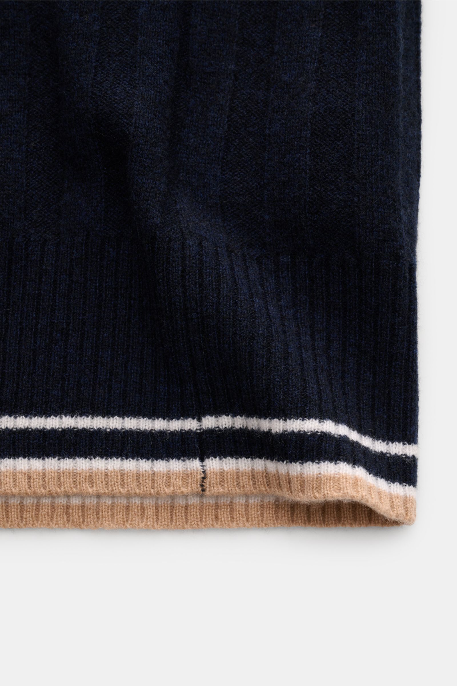 Alt tag (125 characters):
Close-up of navy FTC Cashmere cardigan navy hem with wide rib knit and contrasting beige and white stripes, photographed from the side.

Description:
This luxurious cardigan by environmentally friendly knitwear label FTC is a 