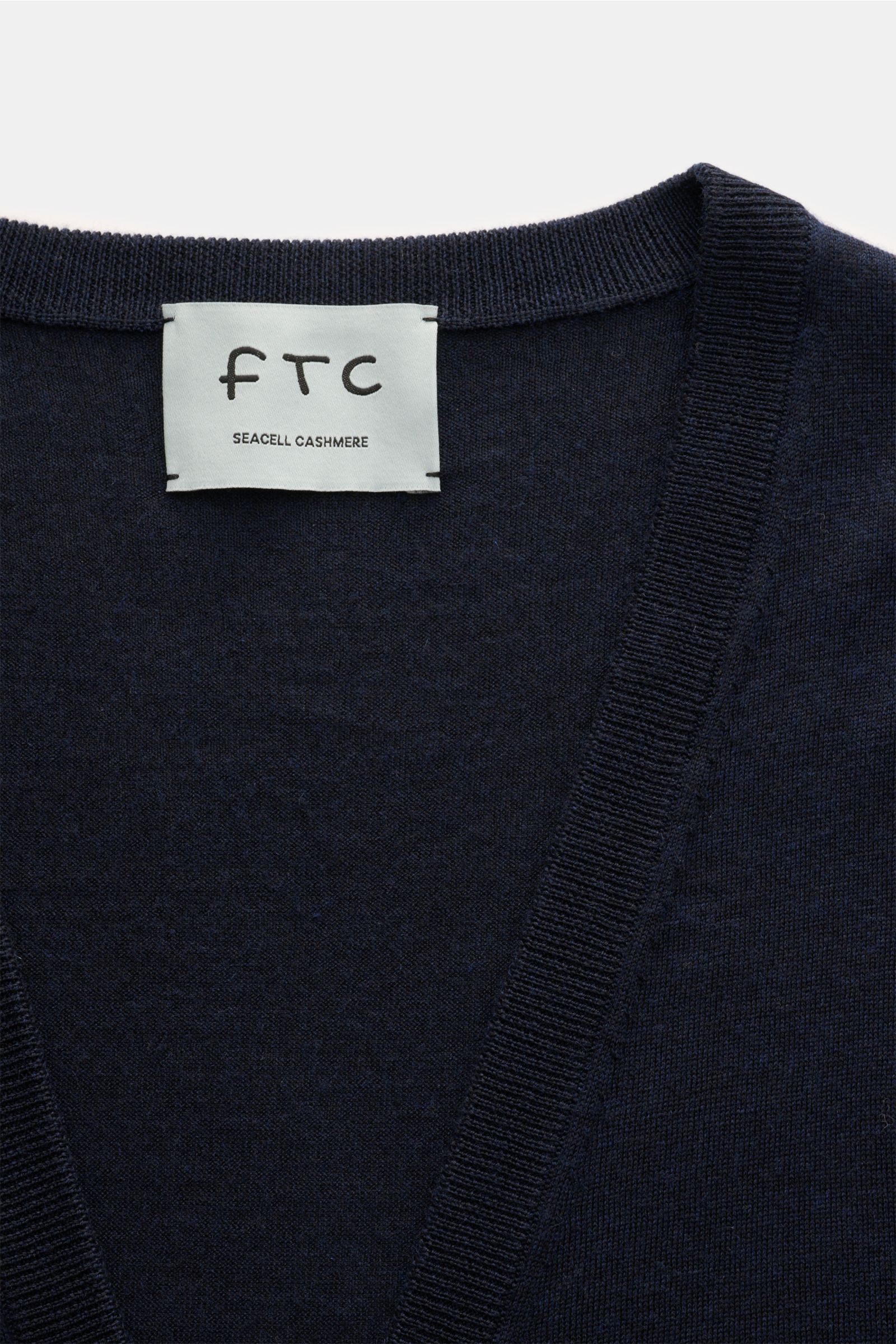 Close-up front view of the FTC Cardigan navy showing the fine knit V-neck and ribbed bands with the FTC label.

This luxurious cardigan by eco-friendly knitwear label FTC is a soft knitwear essential made of fair trade cashmere in a fine blend with Sea