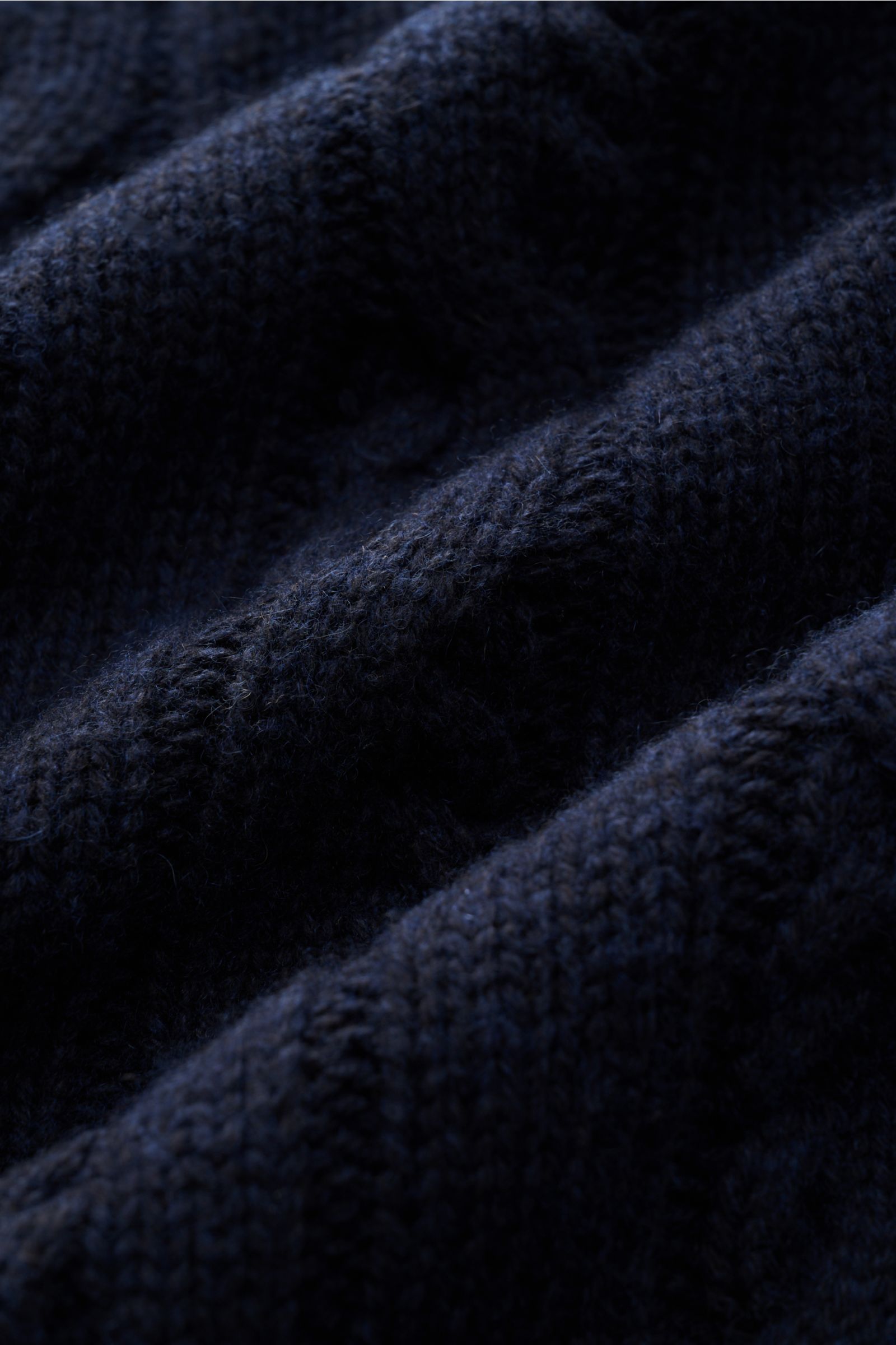 Nahaufnahme des dunkelblauen FTC Cardigan navy mit weichem, mittelgrobem Zopfstrick aus Bio-Baumwolle und Fair-Trade-Cashmere.
