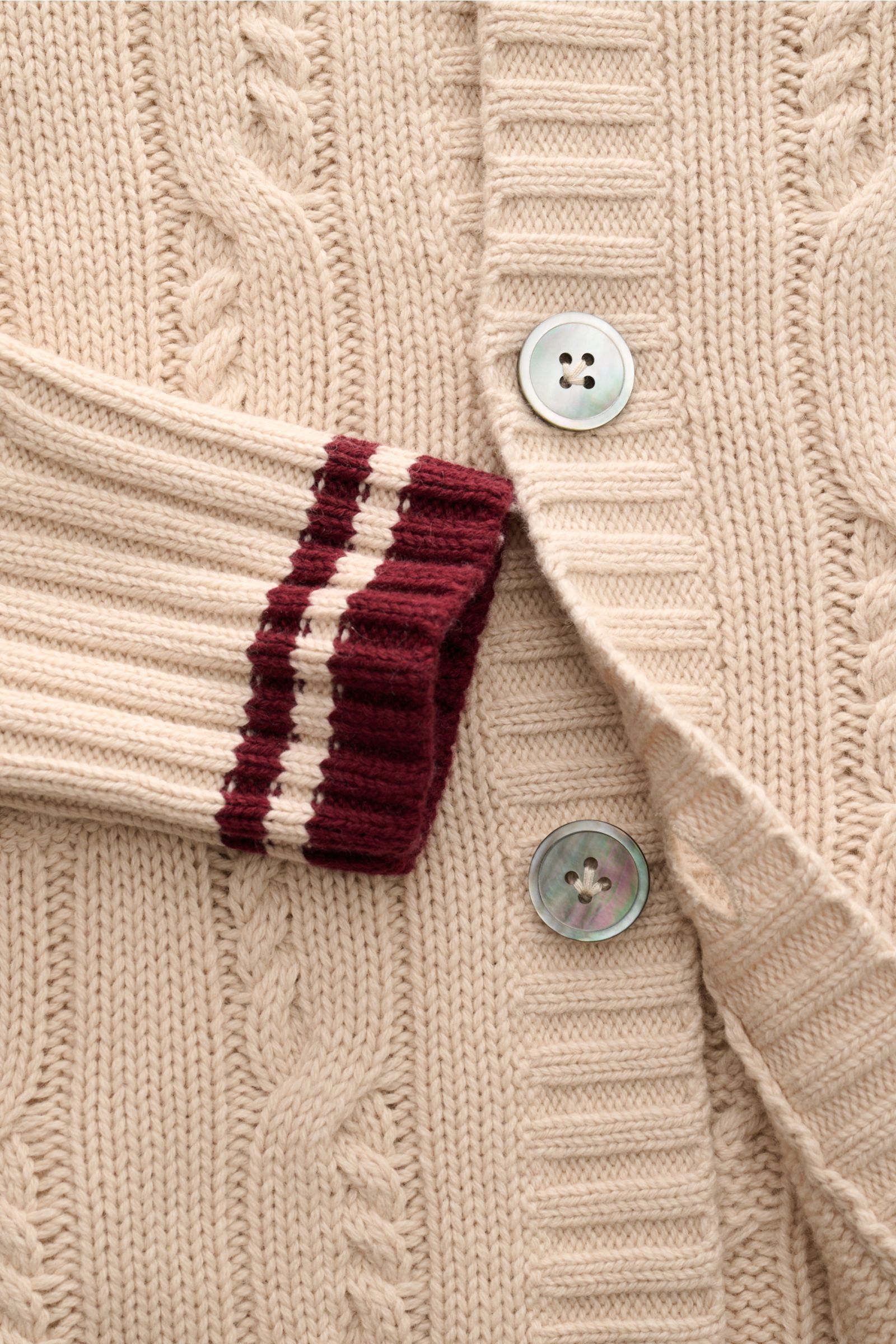 Nahaufnahme des FTC Cardigan beige aus Bio-Baumwolle und Fair-Trade-Cashmere, Zopfstrick, Knopfleiste, Rippbündchen mit Kontraststreifen.