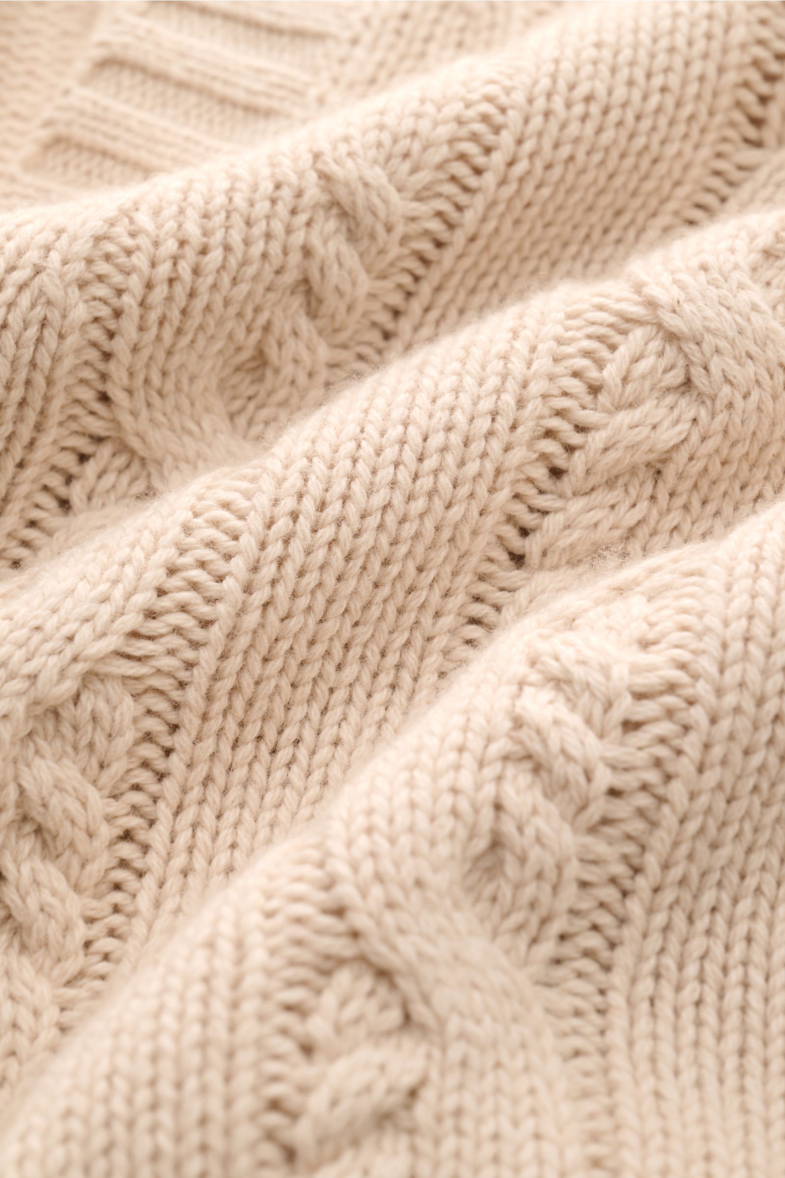 Nahaufnahme des FTC Cardigan beige mit Zopfstrick-Design, weichem Griff aus Bio-Baumwolle und Fair-Trade-Cashmere, mittelgrobes Strickbild.