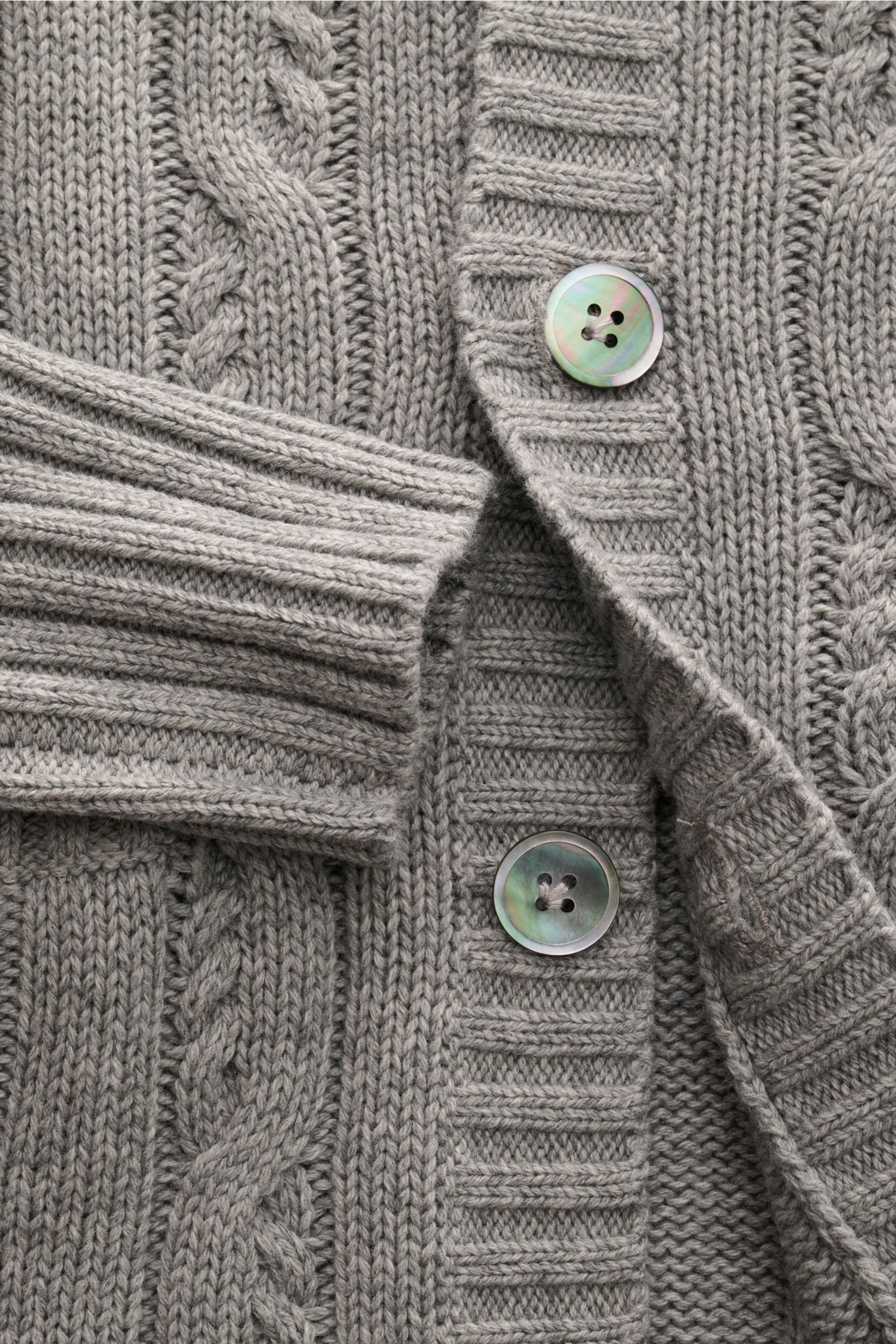 Nahaufnahme des FTC Cardigan grau meliert mit Zopfstrick-Design, Knopfleiste, breiten Rippbündchen und weichem Strick aus Bio-Baumwolle und Fair-Trade-Cashmere.