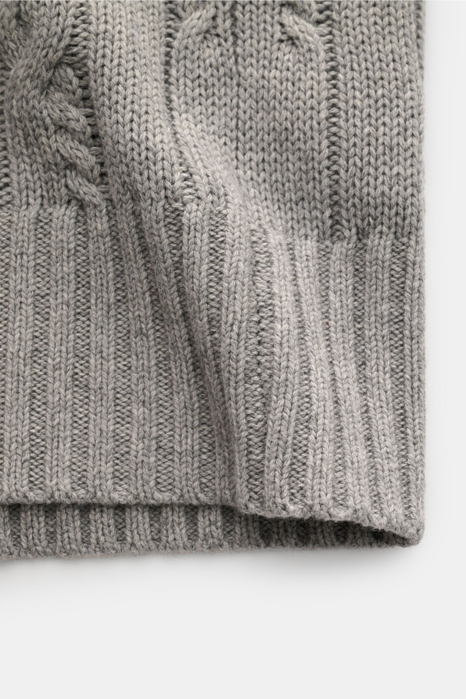 Nahaufnahme des FTC Cardigan grau meliert, fotografiert von oben, zeigt weiches, mittelgrobes Zopfstrickmuster und breite Rippbündchen.