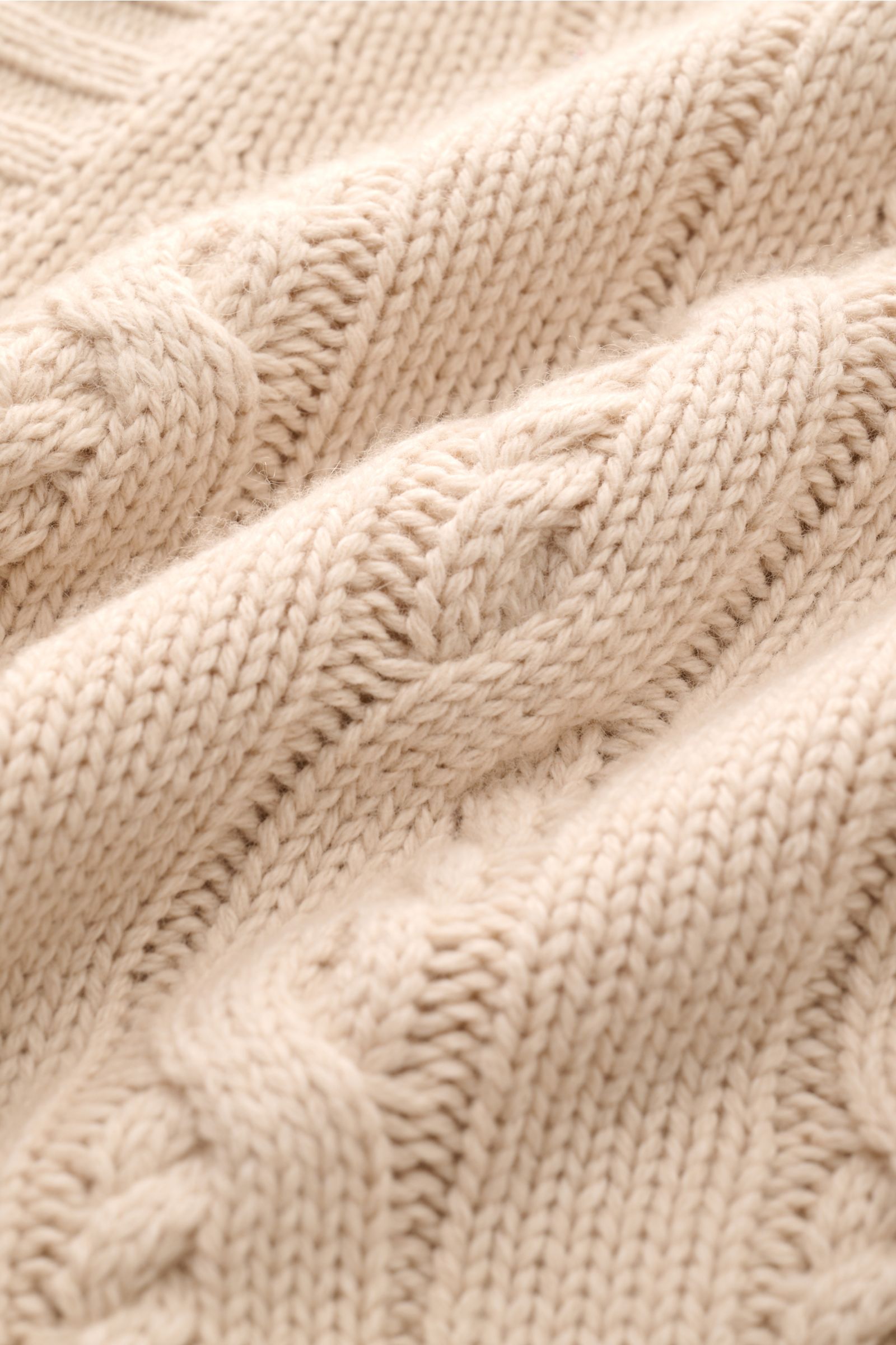 Nahaufnahme des Zopfstrick-Designs und weichen Griffs des FTC Cardigan beige aus Bio-Baumwolle und Fair-Trade-Cashmere.