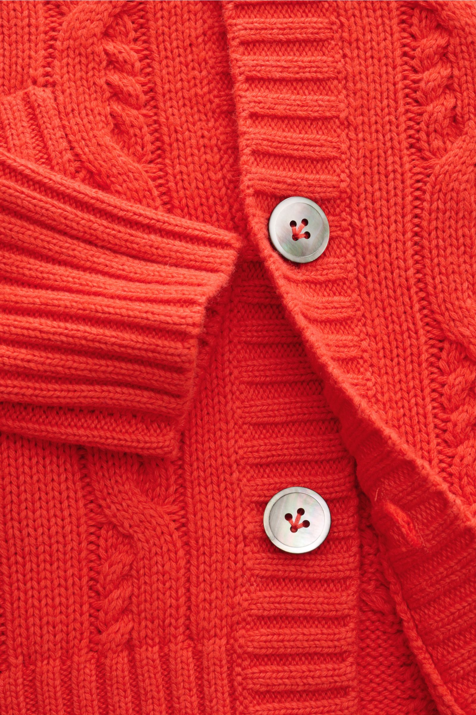 Nahaufnahme des FTC Cardigan hellrot mit Zopfstrick-Design, V-Ausschnitt, Knopfleiste, Leistentaschen, Zungenraglan-Ärmeln und breiten Rippbündchen.