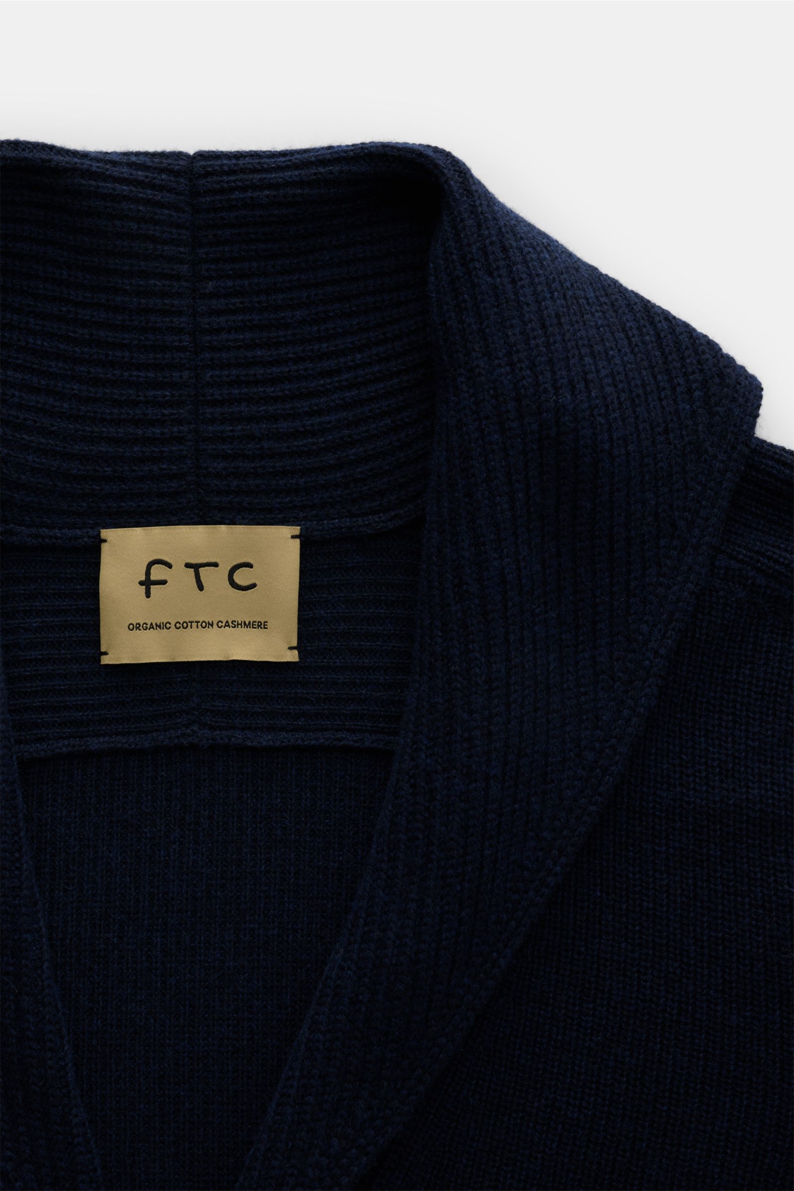 Nahaufnahme des FTC Cardigan navy von FTC mit Schalkragen, V-Ausschnitt, mittelfeinem Strickbild aus Baumwolle und Fair-Trade-Cashmere.