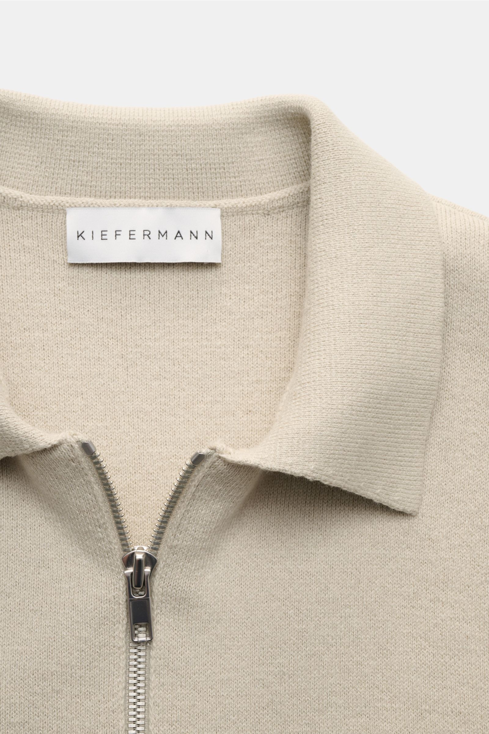 Nahaufnahme der Kiefermann Strickjacke 'Rubern' sand von vorne oben, zeigt Umlegekragen, Zwei-Wege-Reißverschluss und feines Strickbild.