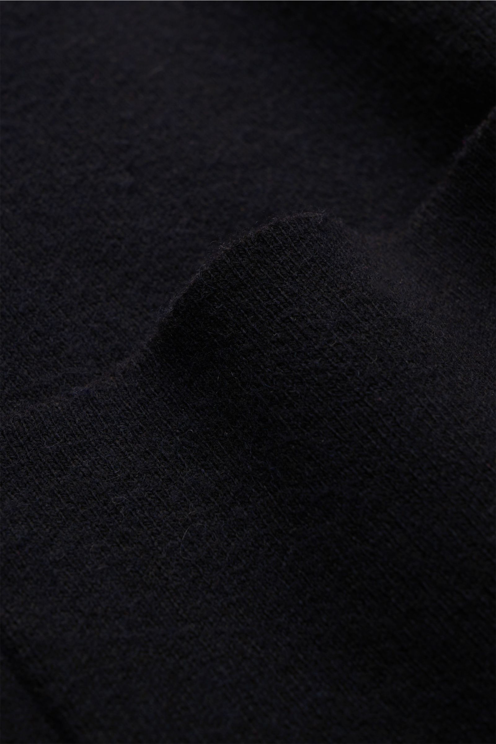 Schwarzer Stoff der Kiefermann Strickjacke 'Rubern' schwarz, feines Strickbild, weicher Griff, Detailaufnahme aus Nahperspektive.