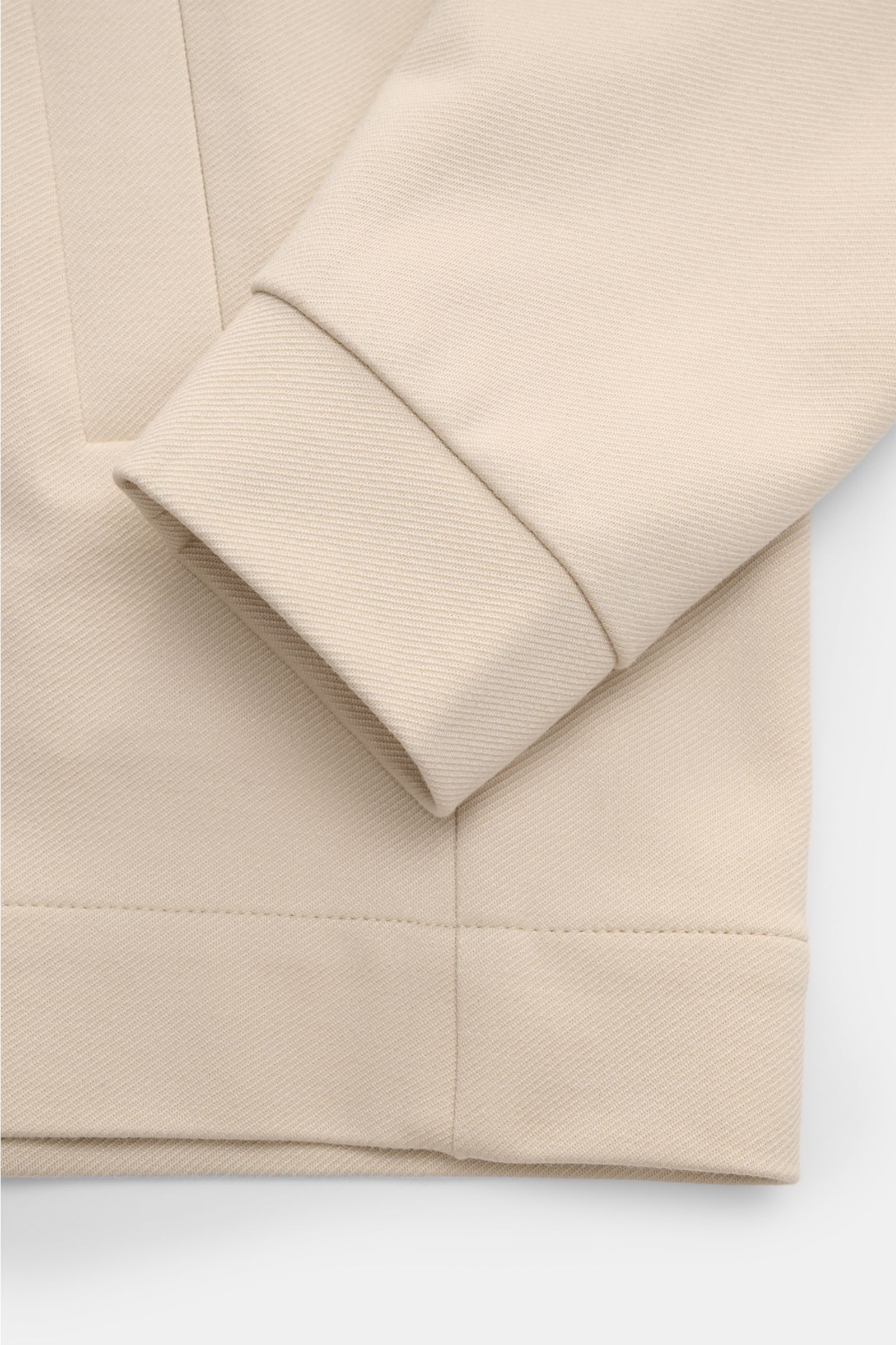 Nahaufnahme der cremefarbenen Kiefermann Strickjacke 'Hunfrid' im Blouson-Stil, Detailansicht von Ärmel und paspelierter Fronttasche.
