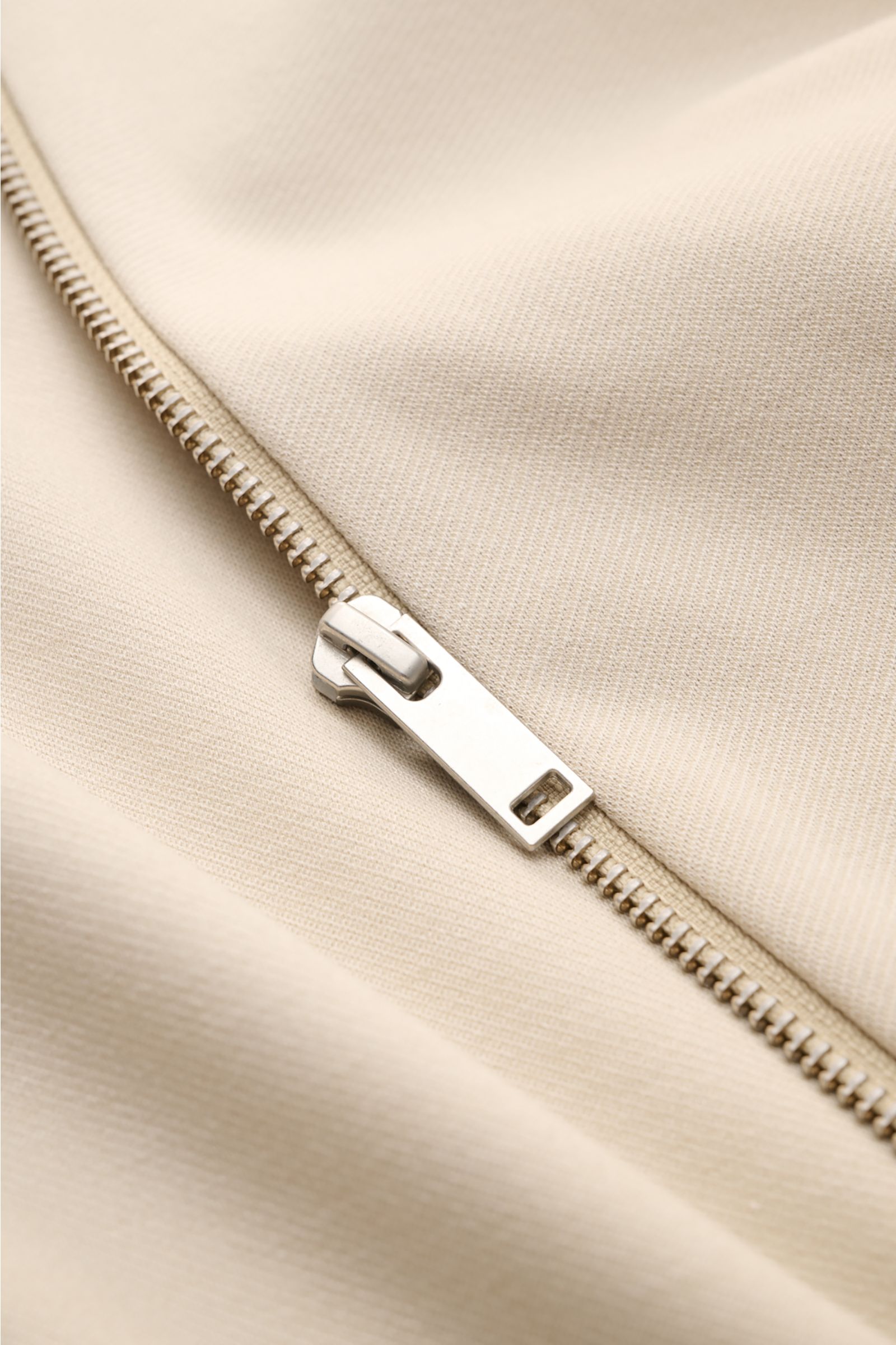 Nahaufnahme der cremefarbenen Kiefermann Strickjacke 'Hunfrid' mit Reißverschluss, weichem Jersey aus Viskose und Microfaser, Slim Fit, Blouson-Kragen und paspelierten Fronttaschen, moderne Layering-Essential-Perspektive.