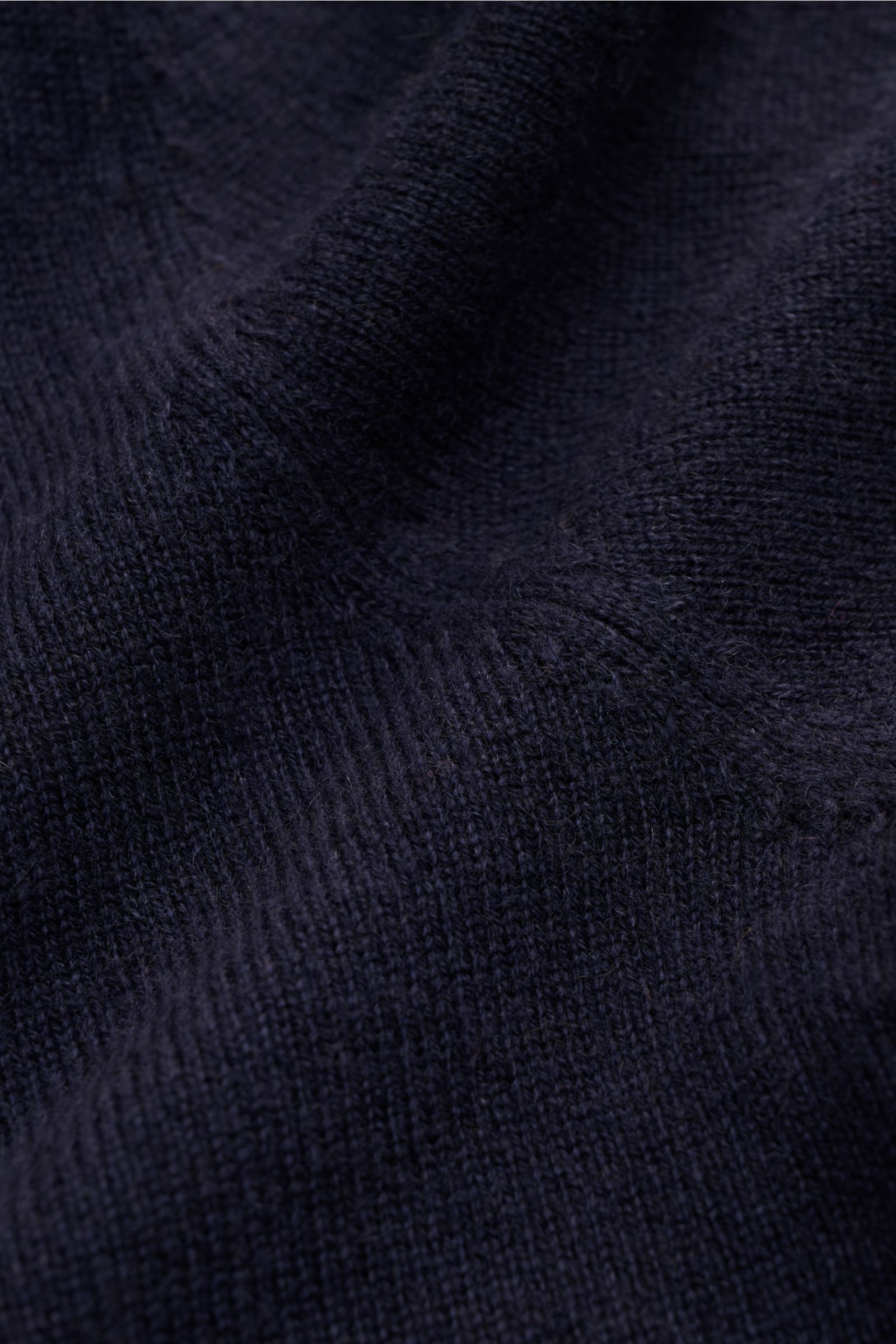 Nahaufnahme des feinen Strickbilds des von Braun Cashmere Cardigan navy aus reinem mongolischem Cashmere mit weichem Griff, fotografiert aus Frontperspektive. Slim Fit, Fünf-Knopf-Leiste und elastische Rippbündchen. Basic für die Übergangszeit und Office-