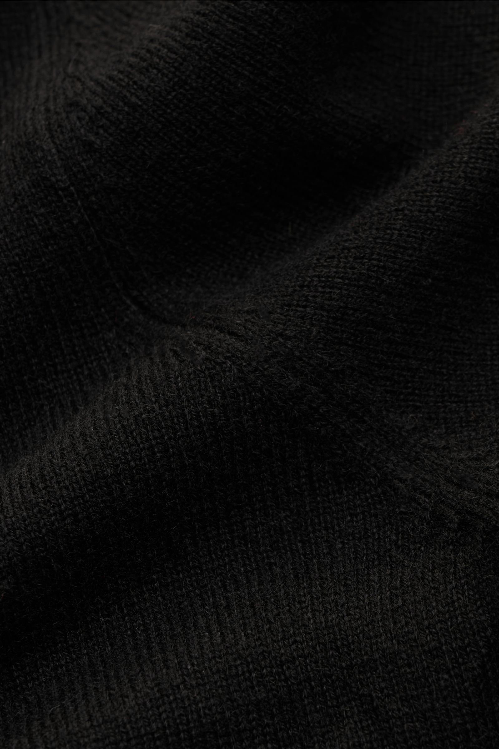 Nahaufnahme des feinen Strickbilds und weichen Griffs des schwarzen von Braun Cashmere Cardigans aus reinem mongolischem Cashmere.