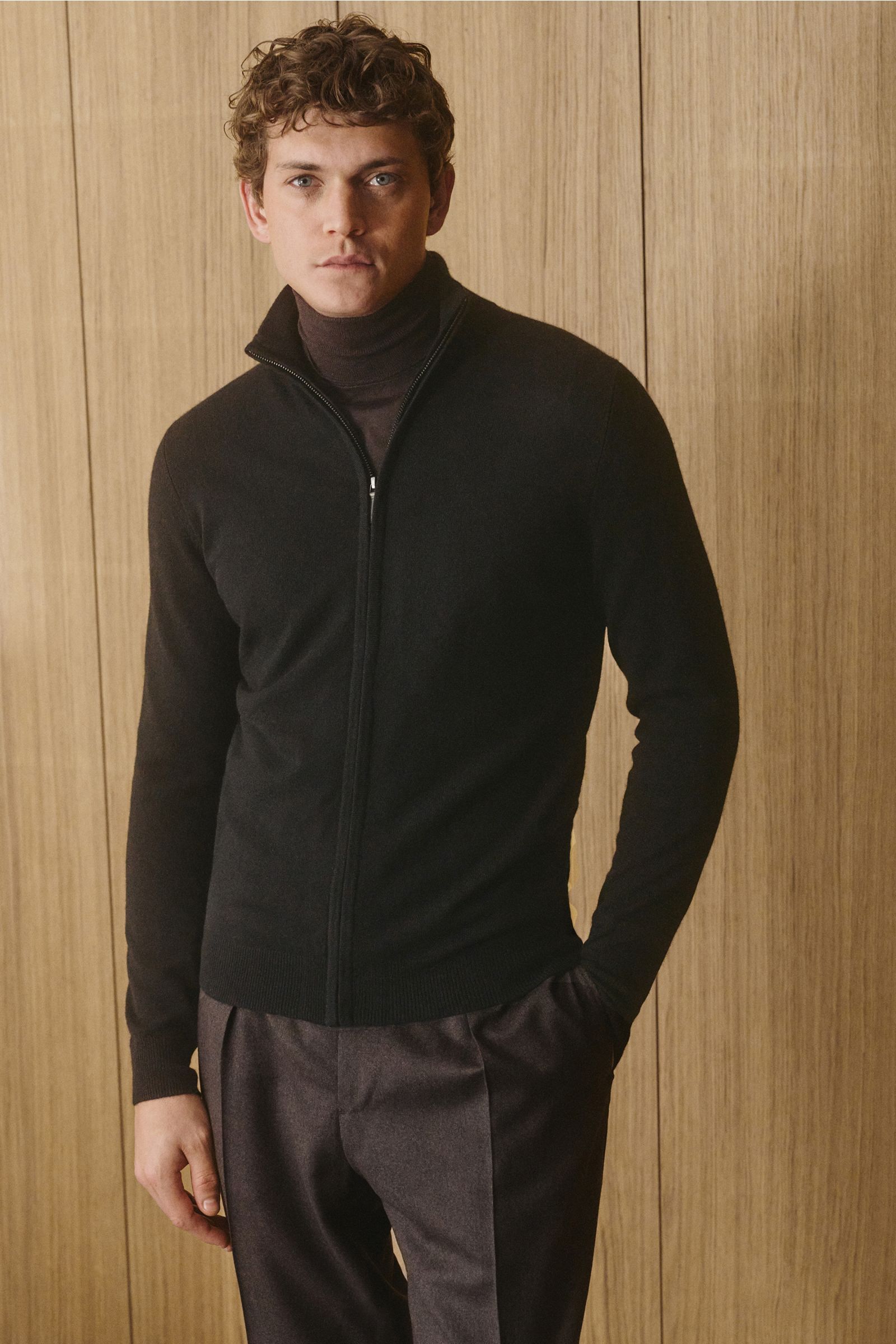 Mann frontal stehend trägt von Braun Cashmere Strickjacke schwarz mit Reißverschluss, Slim Fit, Stehkragen, weichem Griff und Rippbündchen.