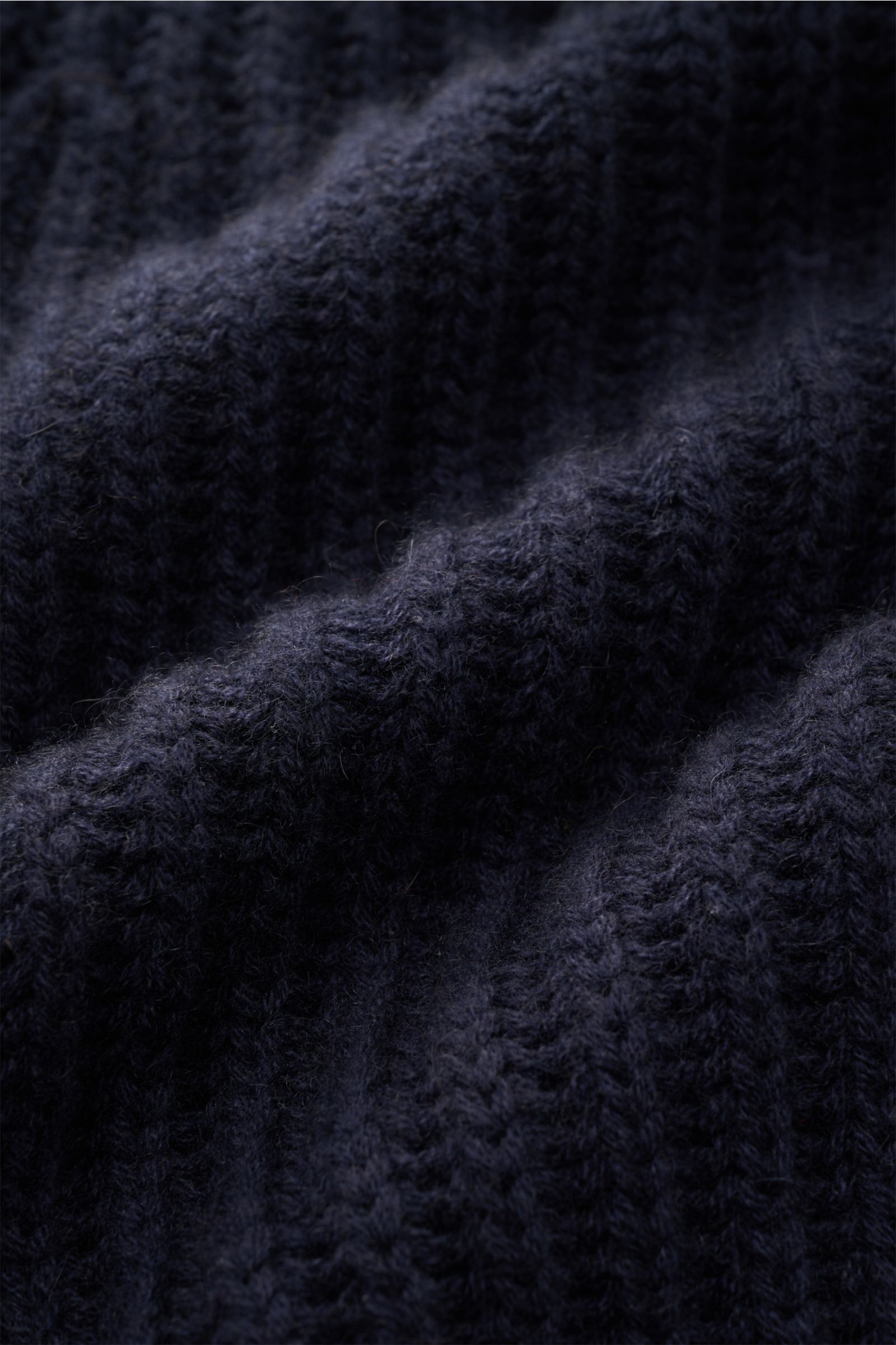 Close-up, textured view of navy brioche stitch knit fabric from the von Braun Cashmere cardigan navy, showcasing soft, chunky pure Mongolian cashmere. How about a less chunky knit? This cardigan in brioche stitch from the VON BRAUN Cashmere collection is 