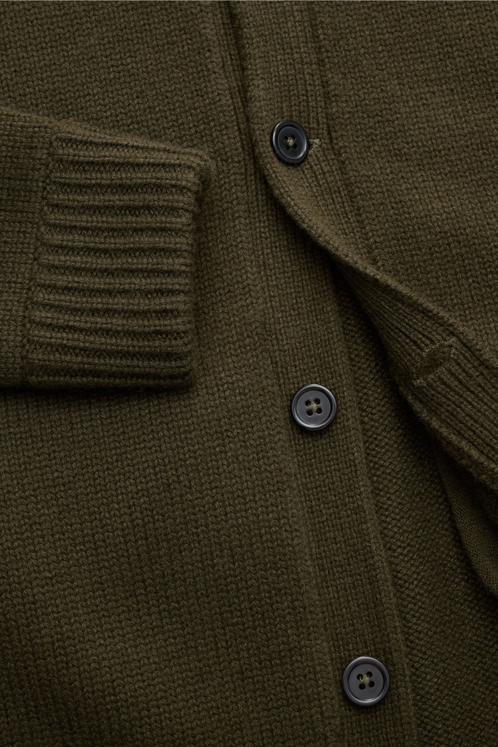Nahaufnahme des von Braun Cashmere Cardigan oliv aus reinem mongolischem Cashmere, mittelfeines Strickbild, Slim Fit, Knopfleiste, Stehkragen und Rippbündchen, schräge Leistentasche, Halbraglan-Ärmel, weicher Griff.