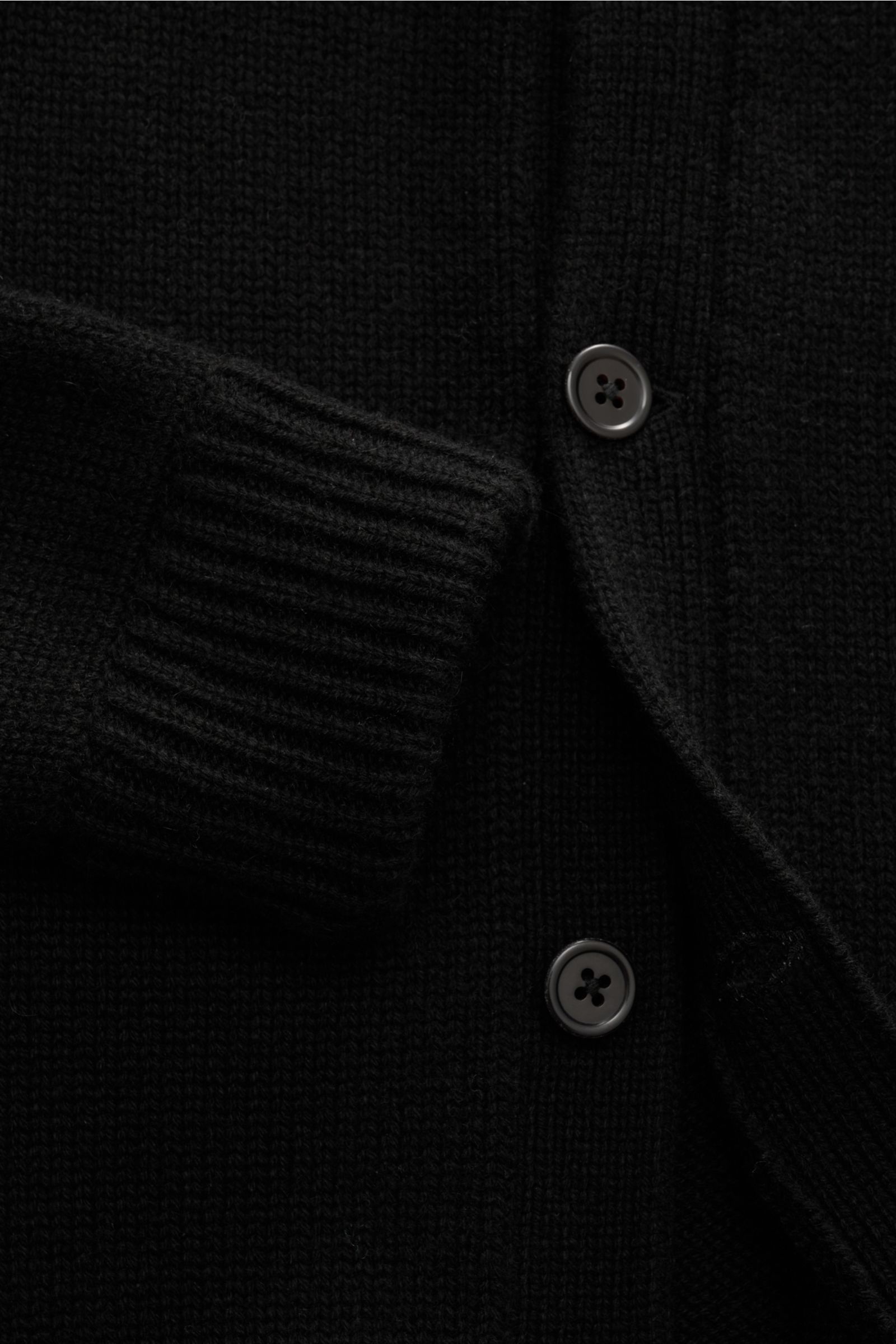 Nahaufnahme des von Braun Cashmere Cardigan schwarz mit mittelfeinem Strickbild, Knopfleiste, Stehkragen, Rippbündchen und Leistentaschen aus mongolischem Cashmere.