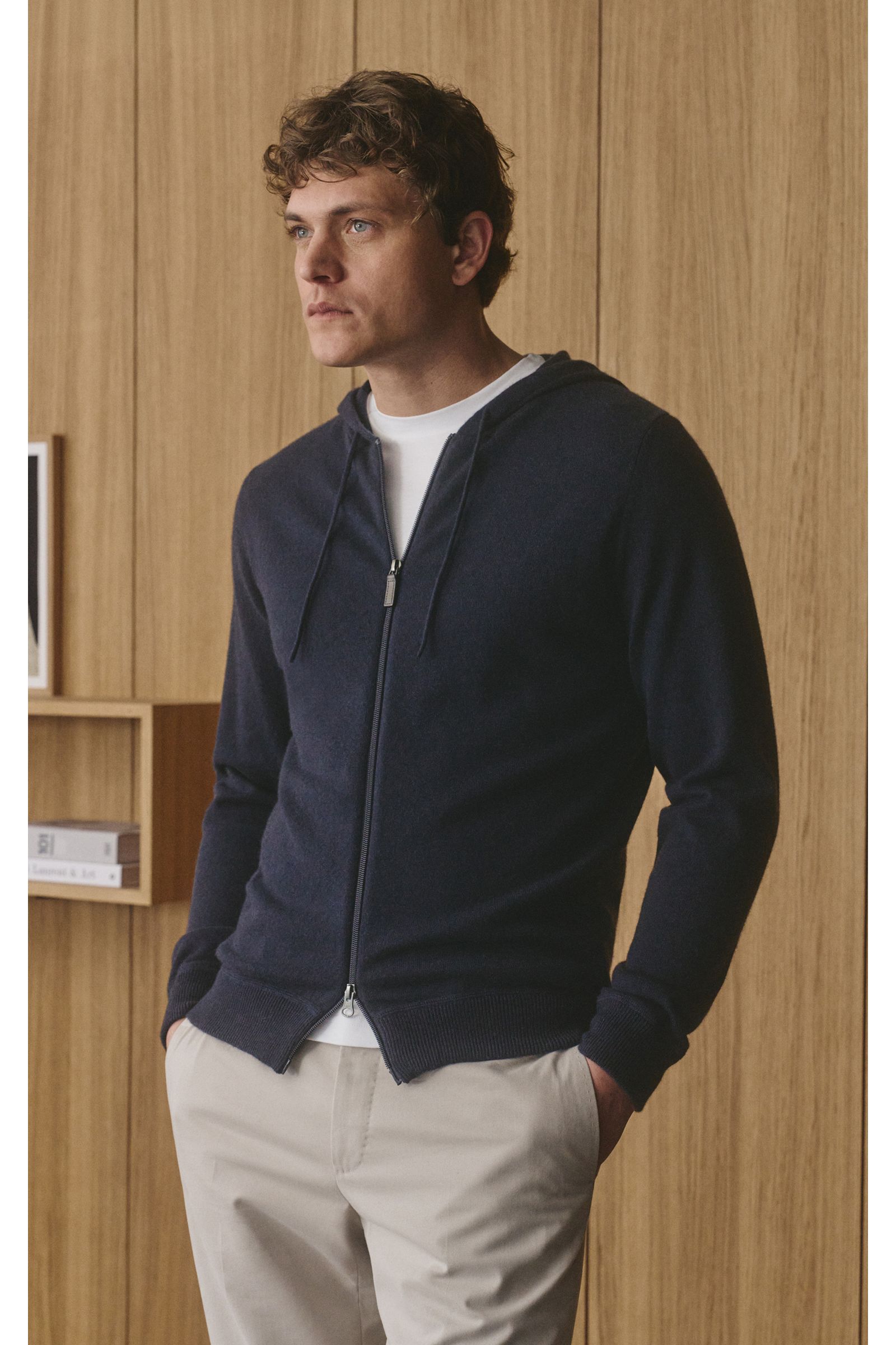 Mann von vorne seitlich fotografiert trägt von Braun Cashmere Strickjacke navy mit Kapuze, Tunnelzug, Zwei-Wege-Reißverschluss, Slim Fit und Rippbündchen.
