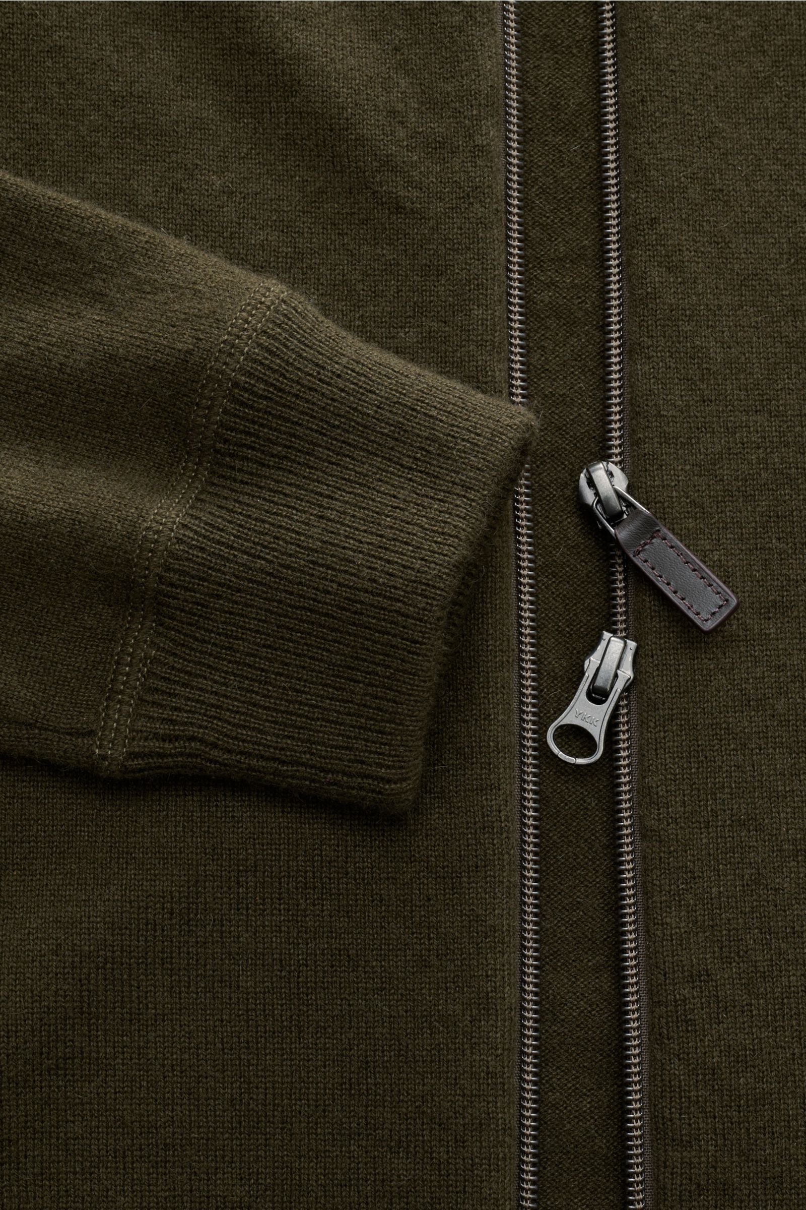 Nahaufnahme der von Braun Cashmere Strickjacke oliv im Slim Fit mit feinem Strickbild, weichem Griff, Kapuze, Rippbündchen und Zwei-Wege-Reißverschluss.