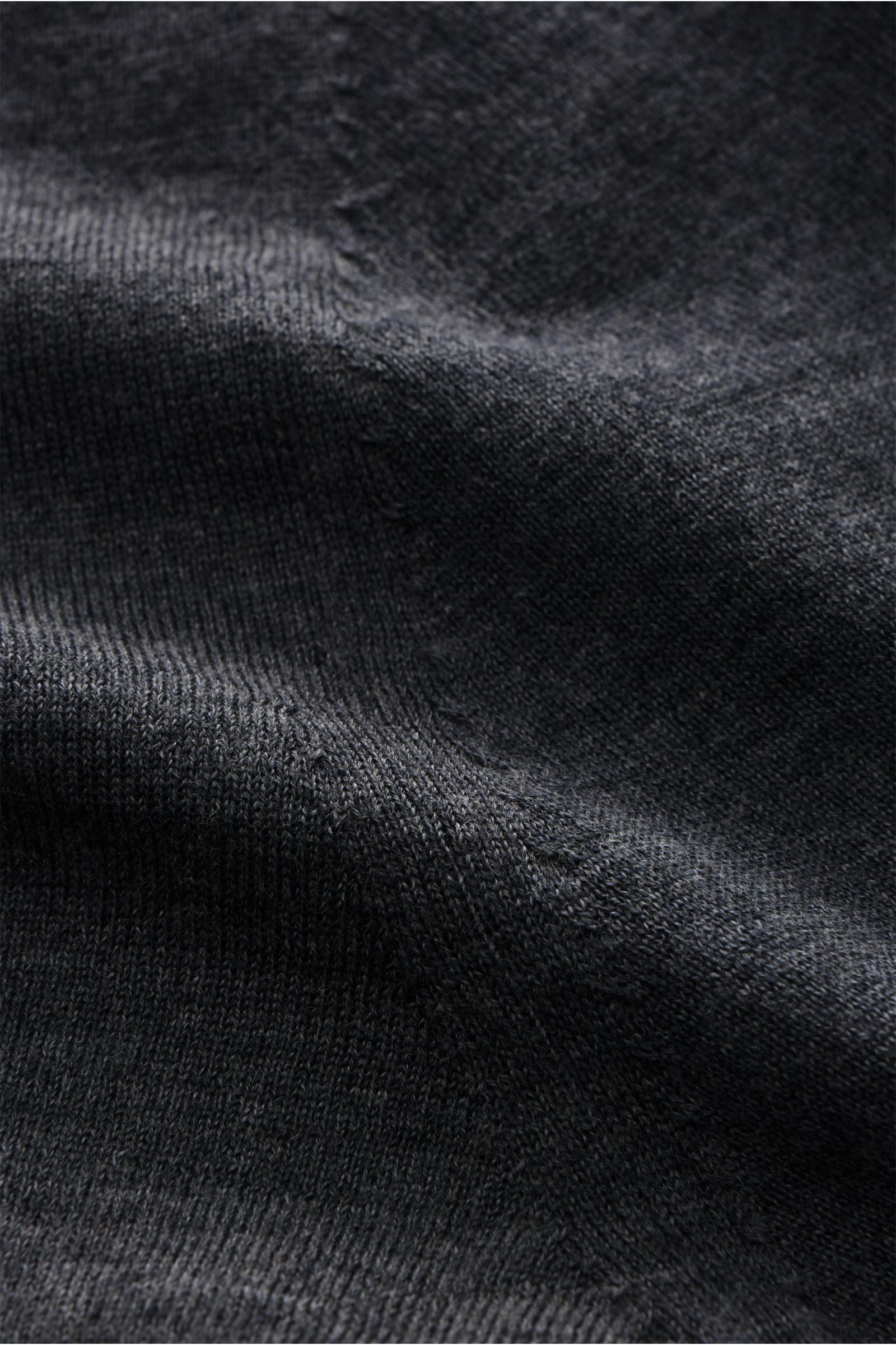 Nahaufnahme des von Braun Merino Cardigan dunkelgrau meliert aus feinem, weichem Merinowoll-Strick mit sehr feinem Strickbild, Regular Fit, Perlmutt-Knöpfen und elastischen Rippbündchen, Detailfoto aus schräger Perspektive.