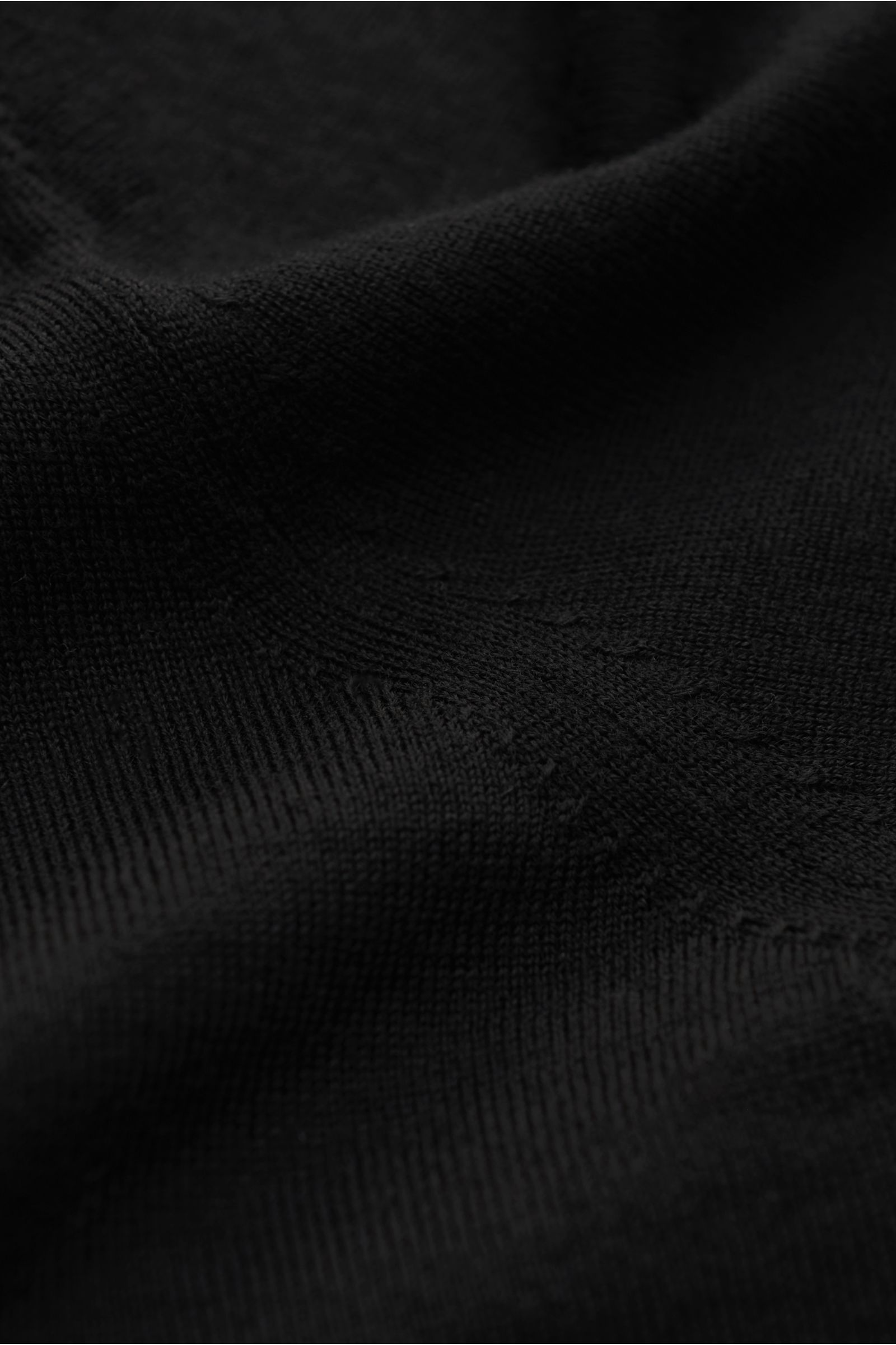 Nahaufnahme des von Braun Merino Cardigans schwarz aus reiner Merinowolle mit feinem Strickbild, weichem Griff und elastischen Rippbündchen.
