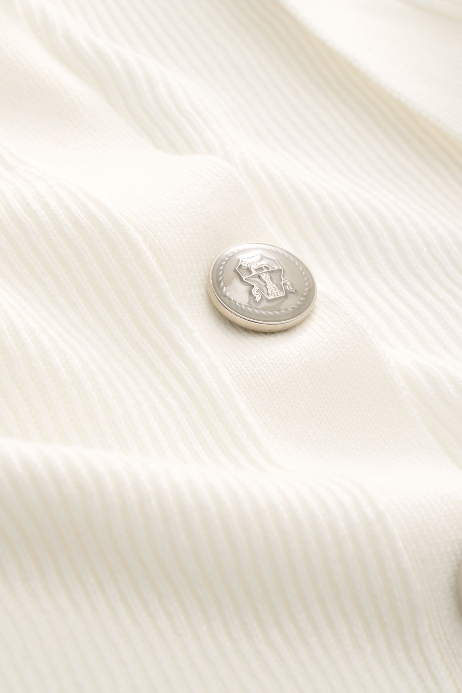 Close-up of a coat-of-arms button on the off-white Brunello Cucinelli Cardigan off-white in soft, medium-fine brioche cotton knit.

Luxury for the office and your downtime: This cardigan in fine brioche knit in soft cotton enhanced with crest buttons b