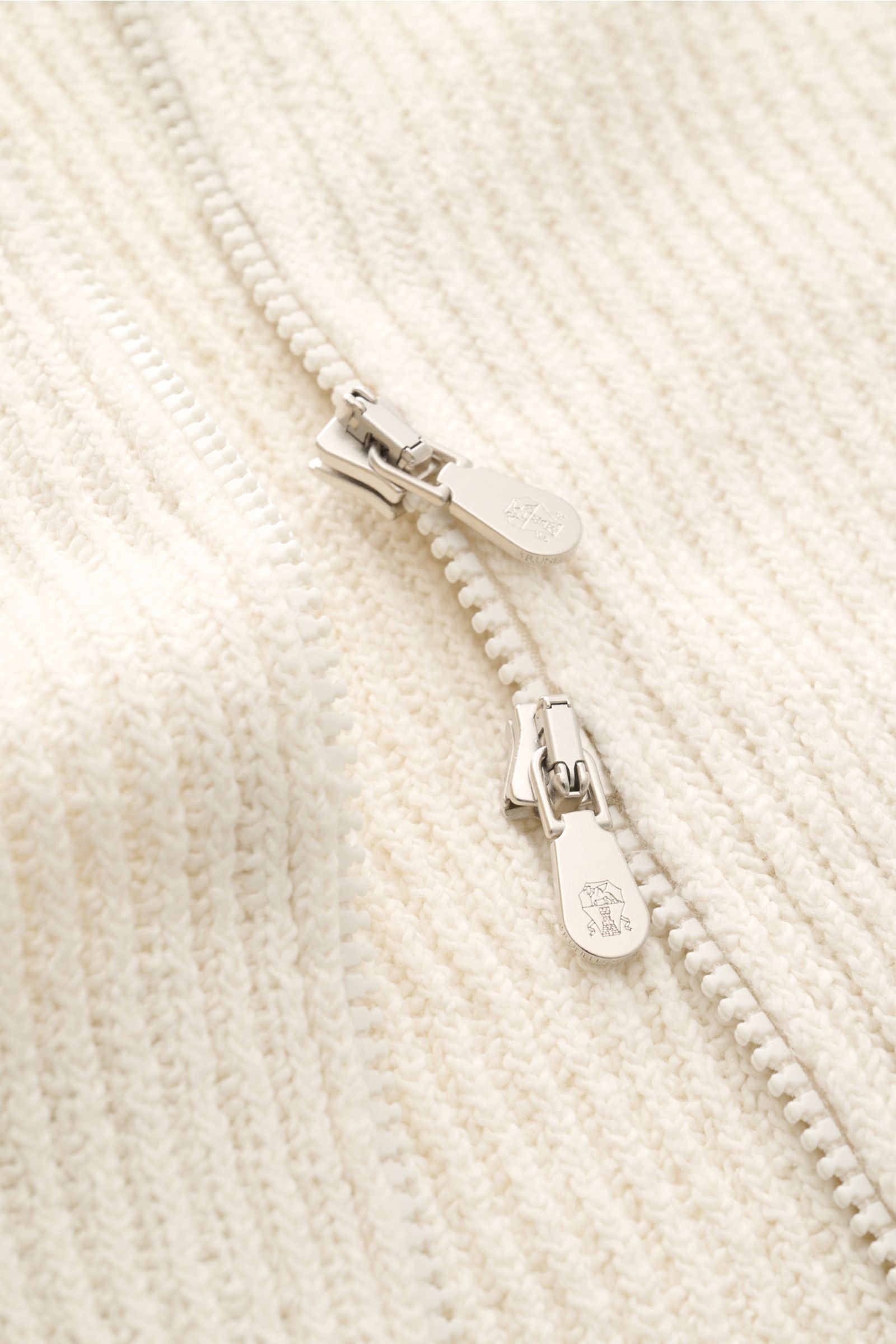 Close-up front top view of the Brunello Cucinelli Cardigan cream showing the two-way silver zipper and soft brioche knit texture.

BRUNELLO CUCINELLI adds luxury to your casual wardrobe with this cardigan in brioche knit in soft cotton enhanced with a 