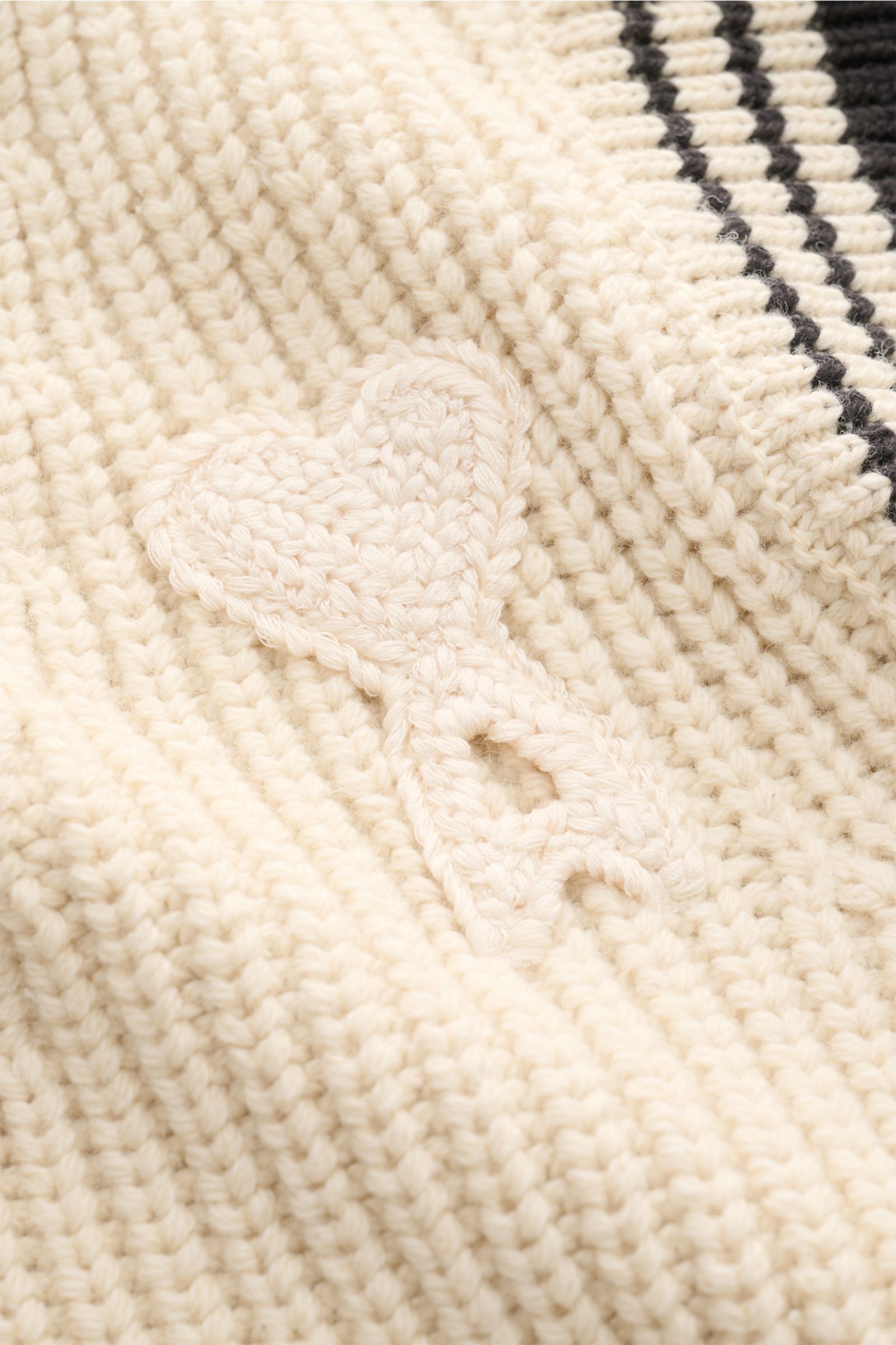 Nahaufnahme des Ami Paris V-Neck Pullunder sand aus grobem Rippstrick mit weichem Griff, V-Neck, Slim Fit und aufgesetztem Ami-Logo.