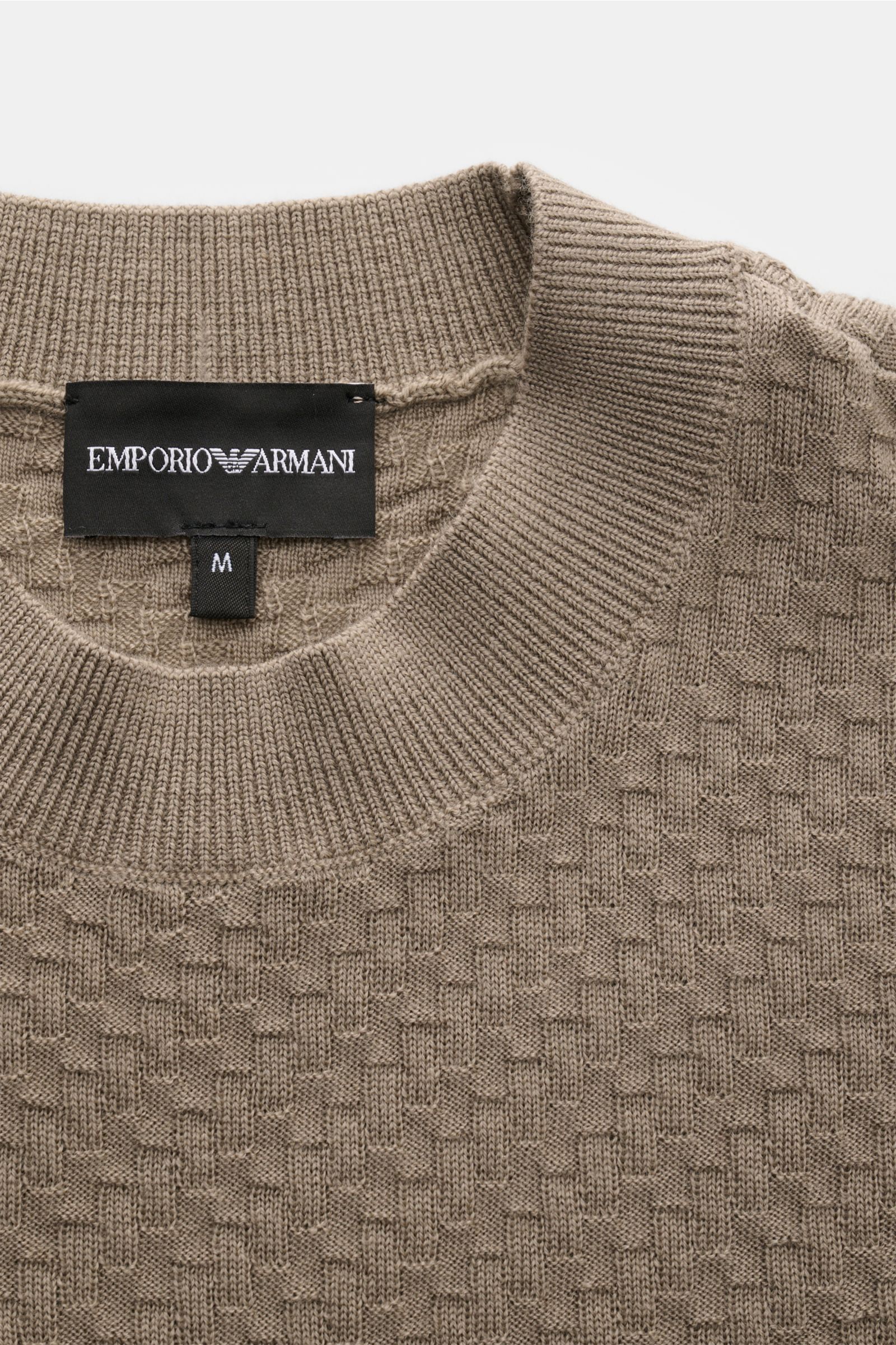 Emporio Armani Crew neck jumper beige shown from a top close-up view, highlighting the textured knit and ribbed bands. Versatile companion: This lightweight short sleeve jumper in pure virgin wool by EMPORIO ARMANI has a subtle textured pattern and is 