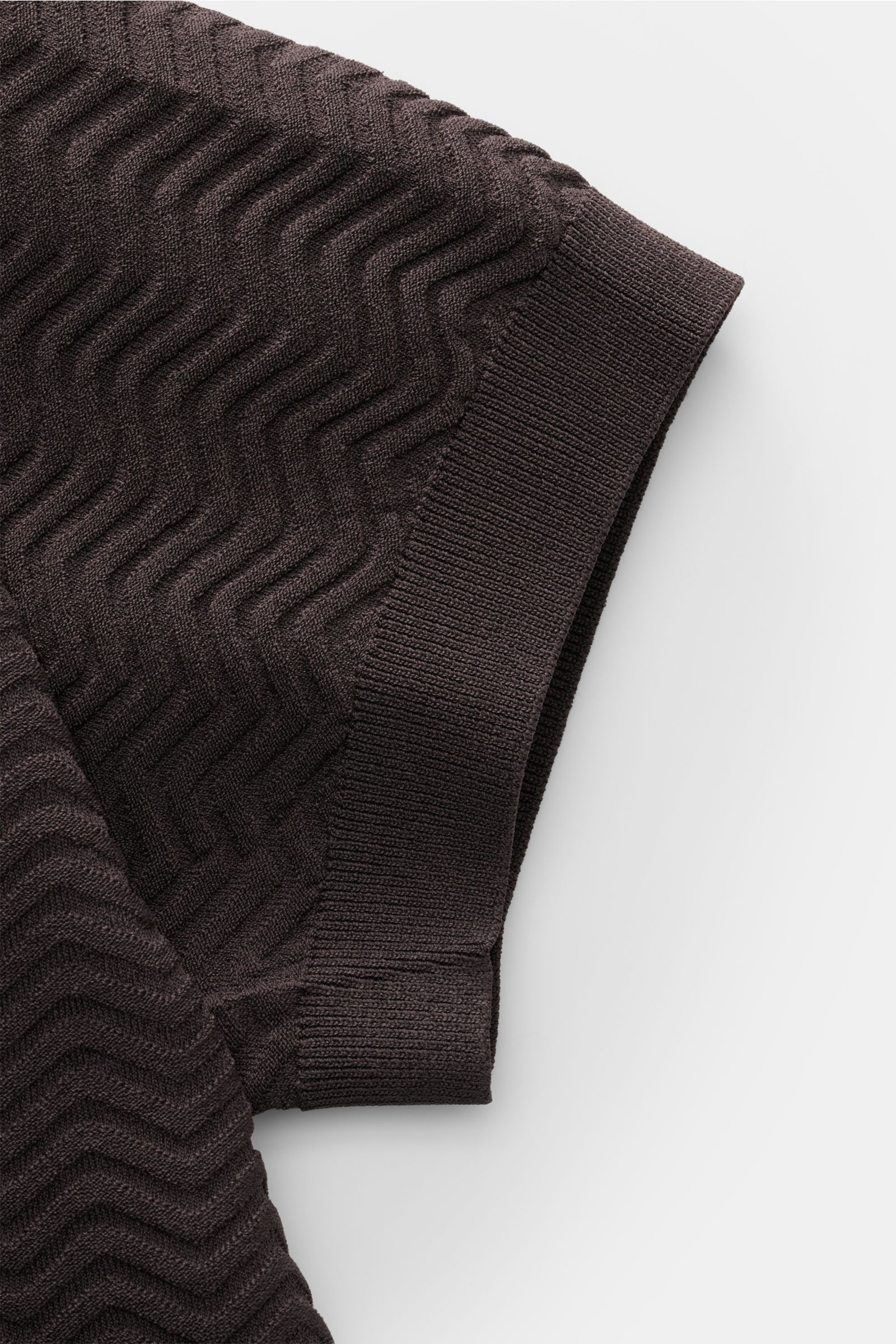 Close-up side view of Emporio Armani Kurzarmpullover dunkelgrau showing elegant textured knit, slim fit, round neckline, ribbed cuffs, and logo stitching. Facettenreicher Hingucker: Der Kurzarmpullover von EMPORIO ARMANI überzeugt mit seiner eleganten Str