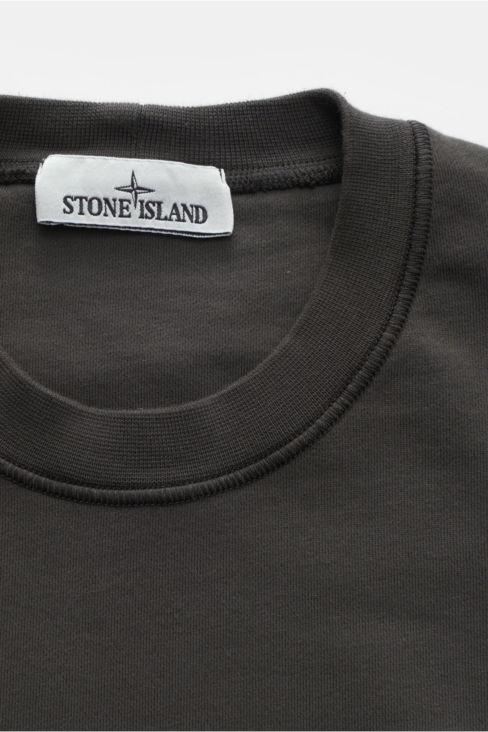 Stone Island Rundhals-Sweatshirt dunkelgrau, Nahaufnahme von Rundhalsausschnitt und Label, Sweat aus reiner Baumwolle, weicher Griff, markante Nahtverarbeitung, garment dyed, Slim Fit, Rundhalsausschnitt, typisches Kompass-Badge, Sweat Innenseite, komfort