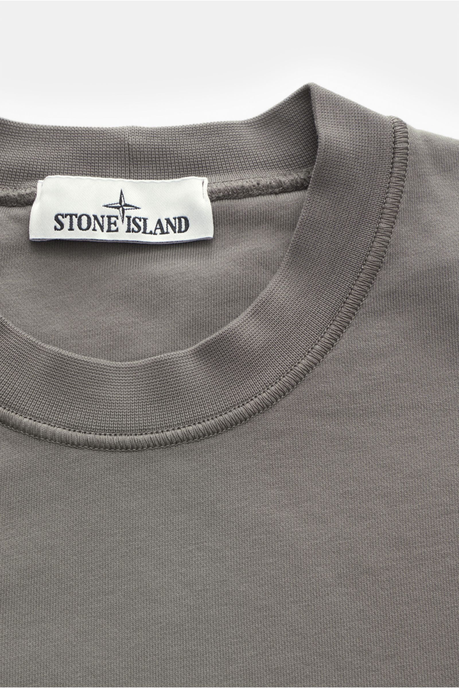 Stone Island Rundhals-Sweatshirt grau, von oben fotografiert, Sweat aus reiner Baumwolle, weicher Griff, markante Nahtverarbeitung, garment dyed, Regular Fit, Rundhalsausschnitt, typisches Kompass-Badge, softe Innenseite, komfortable Rippbündchen.
