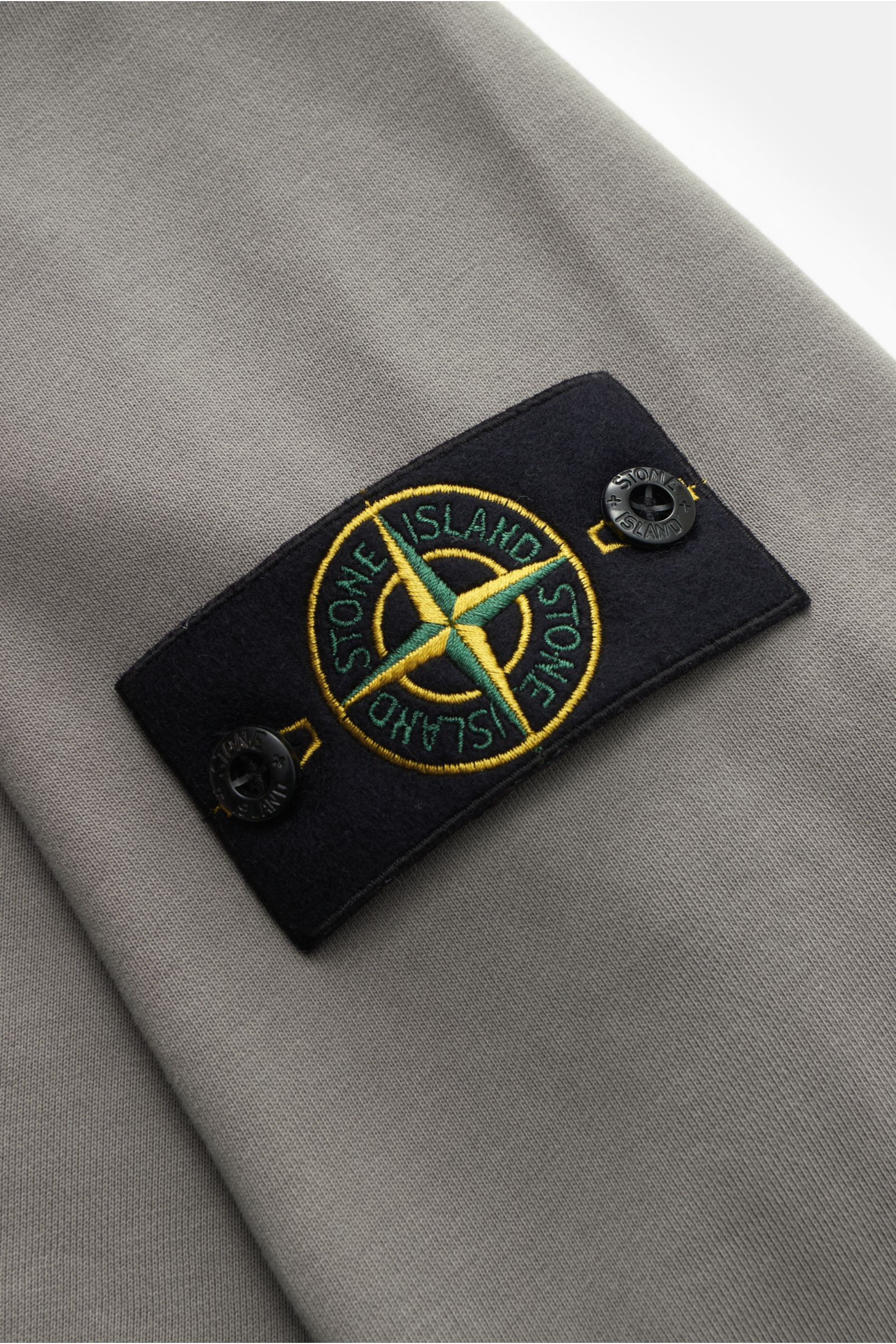 Stone Island Rundhals-Sweatshirt grau, Detailaufnahme der markanten Nahtverarbeitung und typischem Kompass-Badge, Sweat aus reiner Baumwolle, weicher Griff, garment dyed, Regular Fit, Rundhalsausschnitt, softe Innenseite, komfortable Rippbündchen.