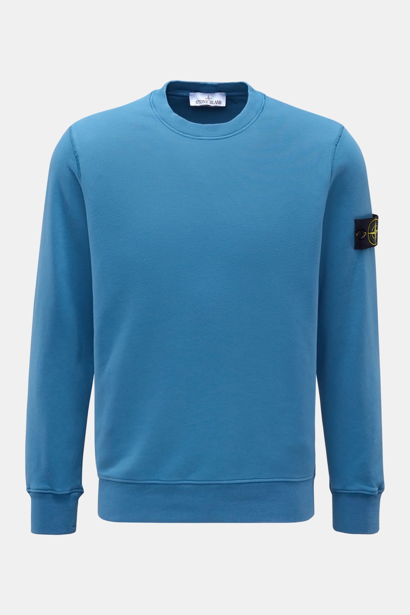 Stone Island Rundhals-Sweatshirt graublau, Slim Fit, aus weicher Baumwolle, garment dyed, mit Kompass-Badge am Ärmel, frontal fotografiert.