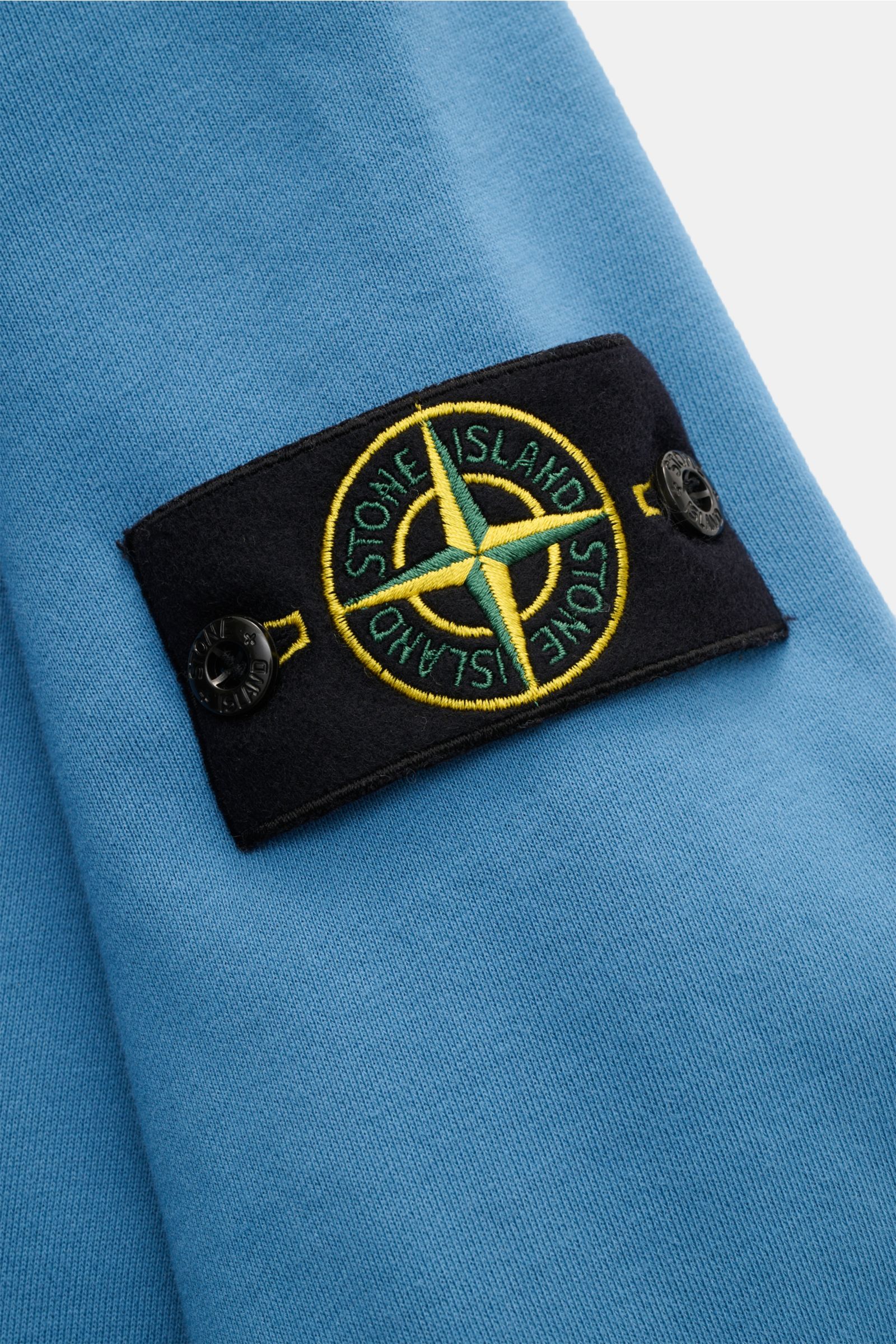 Stone Island Rundhals-Sweatshirt graublau, Detailaufnahme des typischen Kompass-Badges am Ärmel aus reiner Baumwolle, weich, garment dyed.