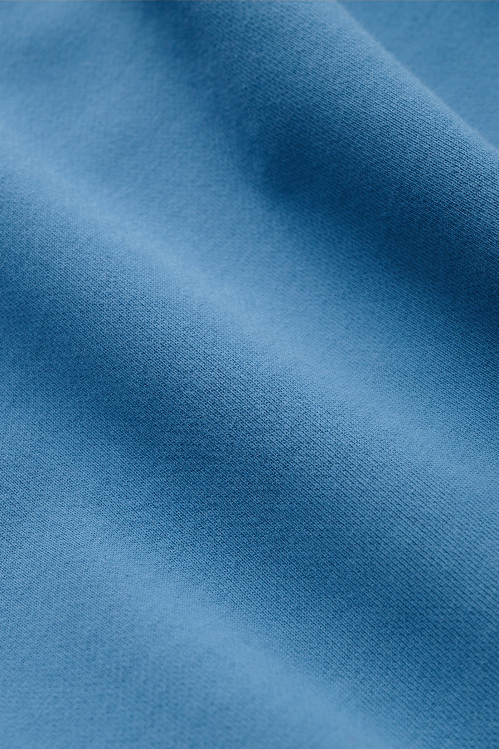 Stone Island Rundhals-Sweatshirt graublau, Slim Fit, aus weicher, garment dyed Baumwolle, Detailaufnahme der Stoffstruktur aus naher Perspektive.