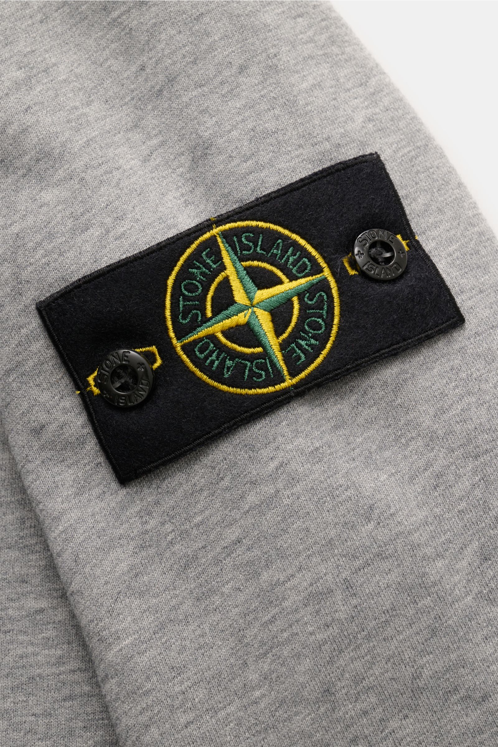 Stone Island Rundhals-Sweatshirt grau meliert, Detailansicht Ärmel mit typischem Kompass-Badge, Sweat aus reiner Baumwolle, weicher Griff, markante Nahtverarbeitung, garment dyed, Slim Fit, Rundhalsausschnitt, komfortable Rippbündchen.
