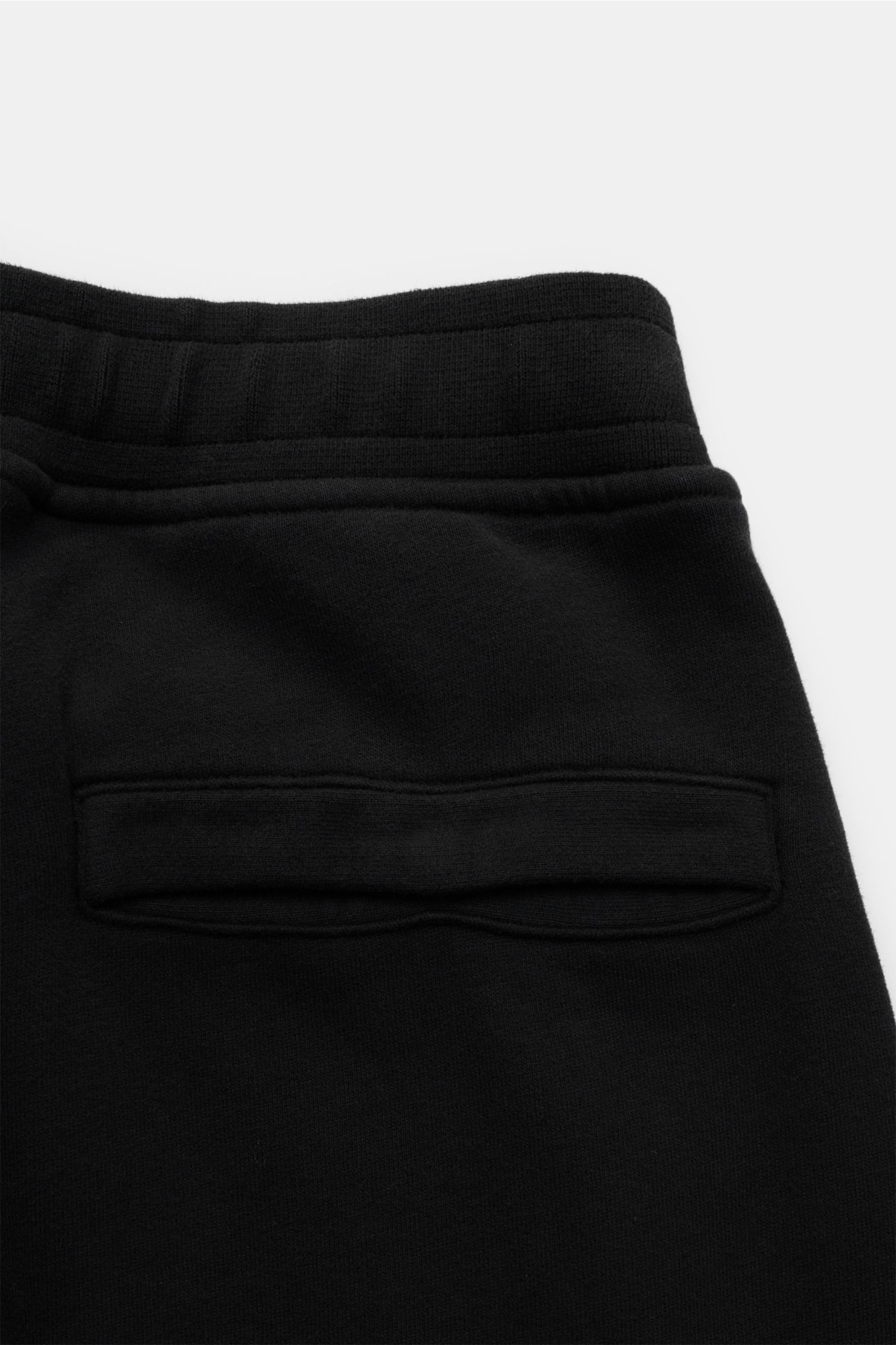 Schwarze Stone Island Sweathose aus reiner Baumwolle, garment dyed, schmal zulaufend, elastischer Bund, Gesäßtasche mit Druckknopf, Kompass-Badge, Detailansicht von hinten.