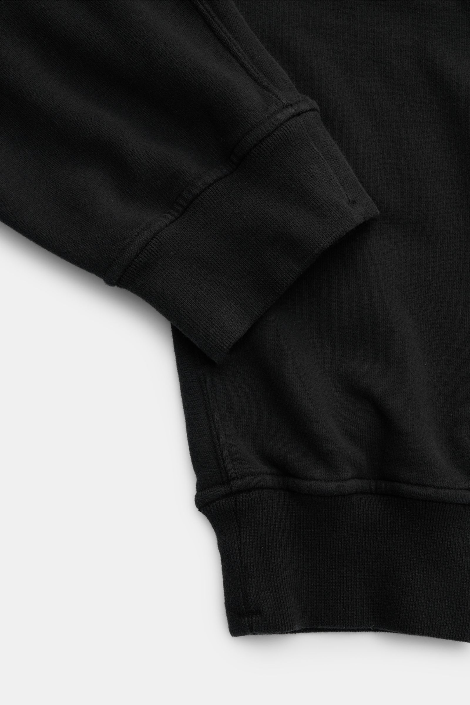 Schwarz fotografierte Detailansicht der Stone Island Sweathose schwarz mit elastischem Bund, Rippbündchen, weichem Baumwollstoff und Kompass-Badge.